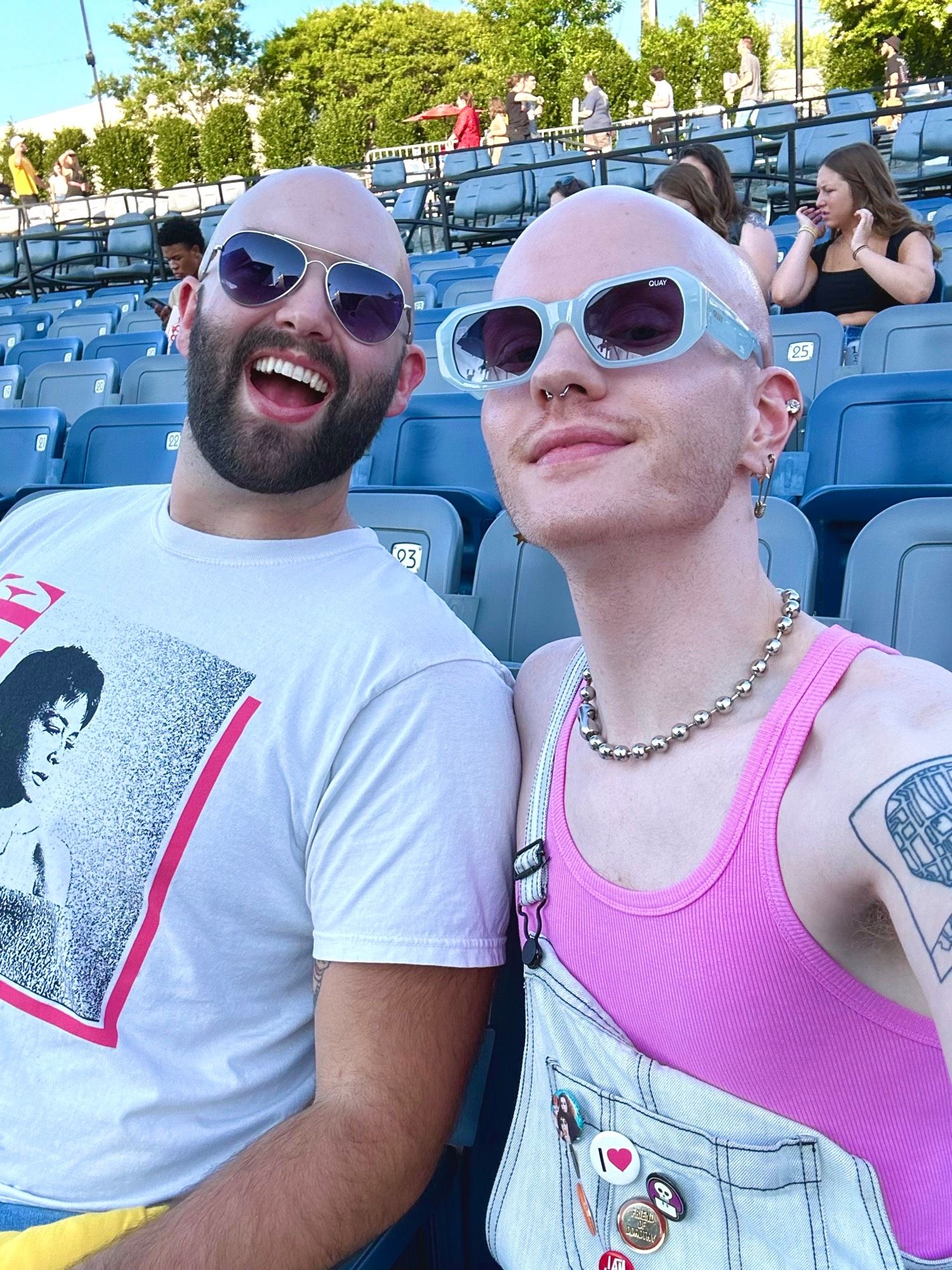 two bald gays seated waiting for a concert 