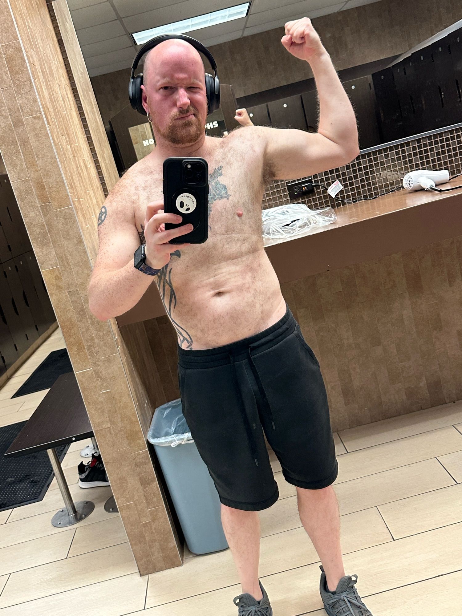 A selfie of me shamelessly flexing one arm as I pose (a sad attempt at that) in the locker room at the gym.