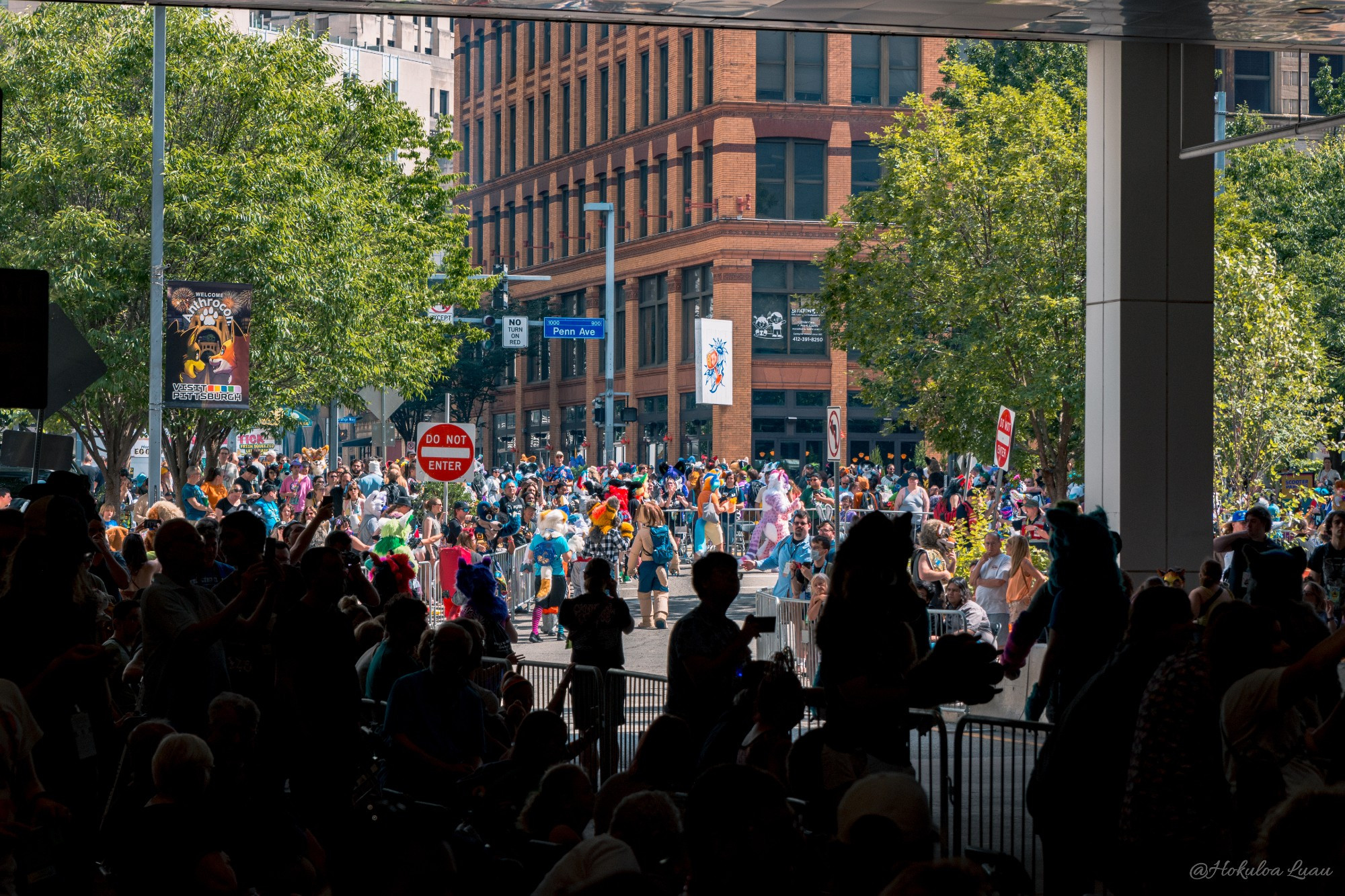 An overview shot of the Anthrocon 2024 Fursuit Parade and crowd, facing the corner of 10th Street and Penn Avenue.