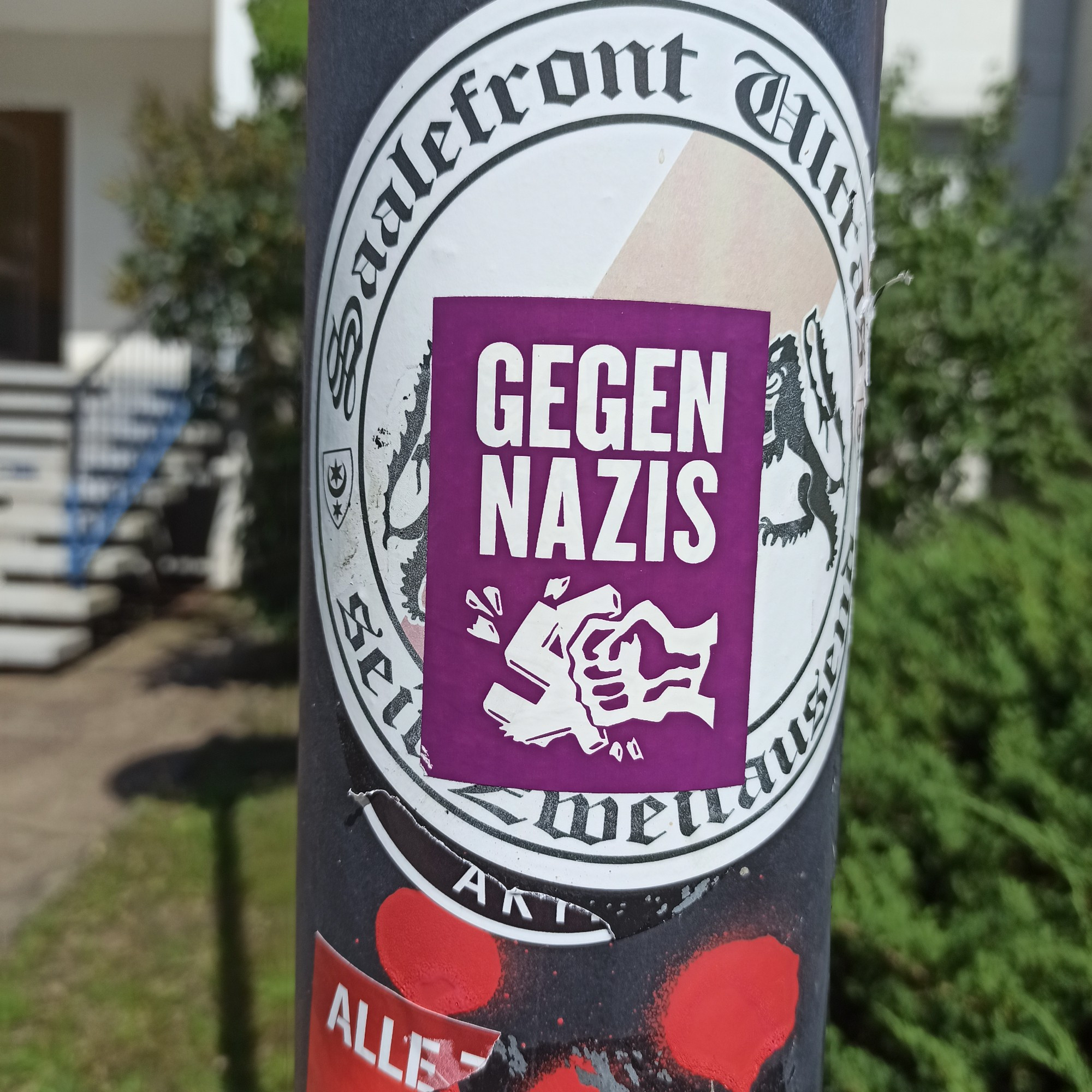 Pinker Antifa Sticker auf Laternenmast. Eine Faust zerschlägt ein Hackenkreuz zu lesen ist Gegen Nazis