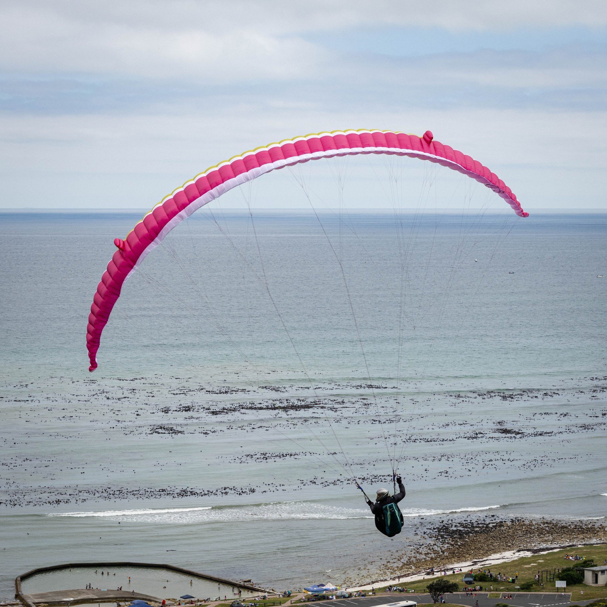 Paraglider in flight, just after launching from the side of the M65 road overlooking the Soetwater Resort, south of Kommetjie. The resort's tidal pool is visible at the bottom of the image