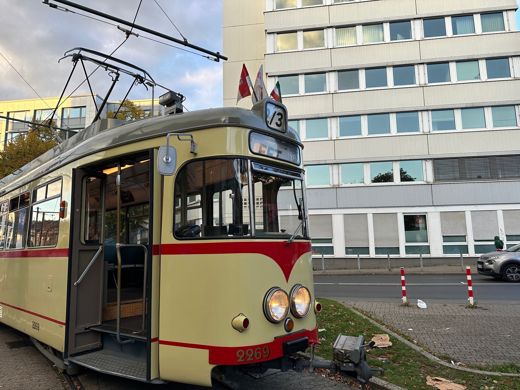 Eine historische Straßenbahn steht vor einem Betongebäude