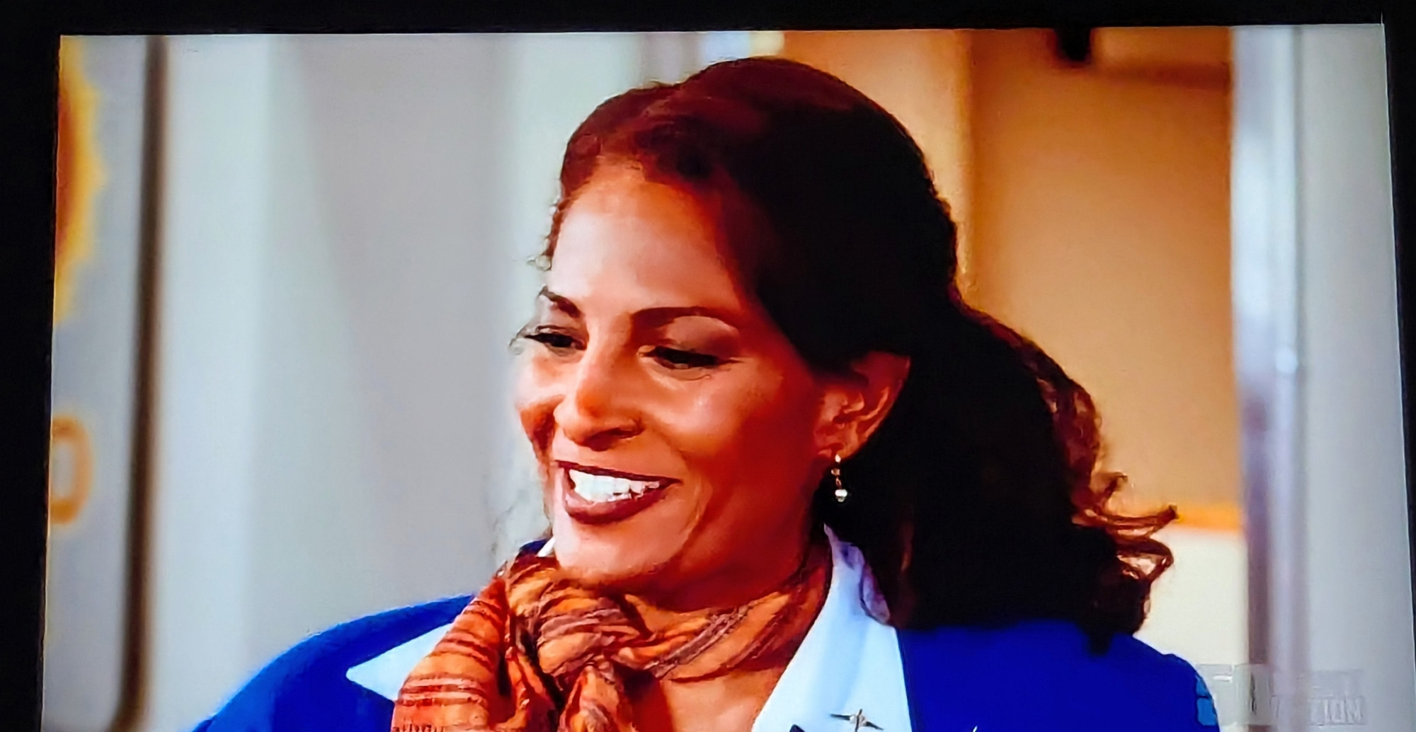 Pam Greer as Jackie Brown in blue airline uniform with brownish tan scarf around neck 