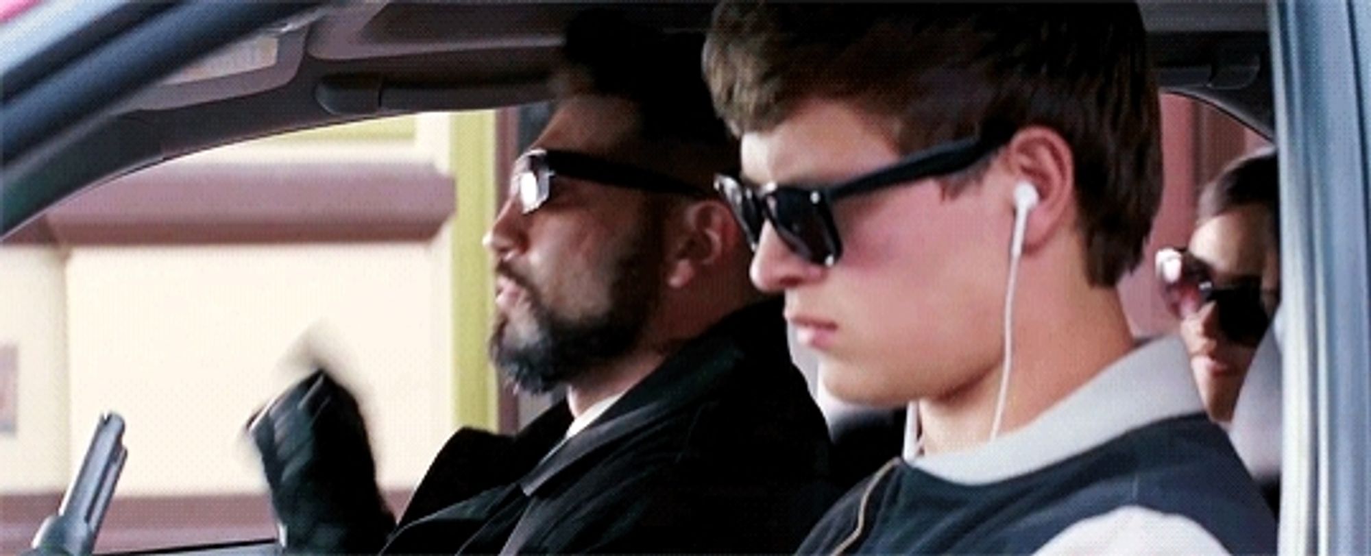 A gif from the film Baby Driver. The view is through the driver's side window of a car. Jon Bernthal as Griff is seated in the passenger seat. He points forward and Baby (played by Ansel Elgort) in the driver's seat, accelerates backwards out of frame.