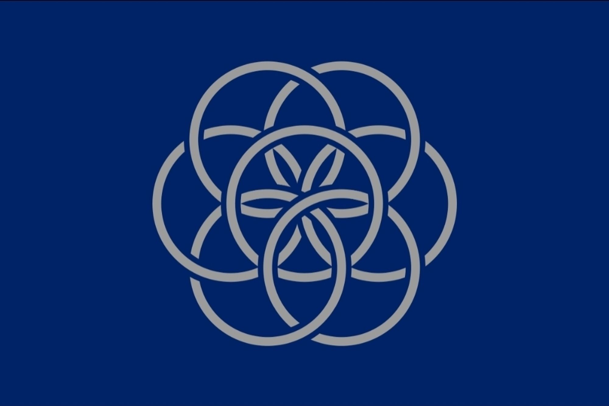 A 3:5 blue flag with a navy blue background and seven interlocking white rings with one ring in the centre and three sets of two rings above, beside, and below the centre ring where each ring interlinks with the rings beside it as well as the centre ring