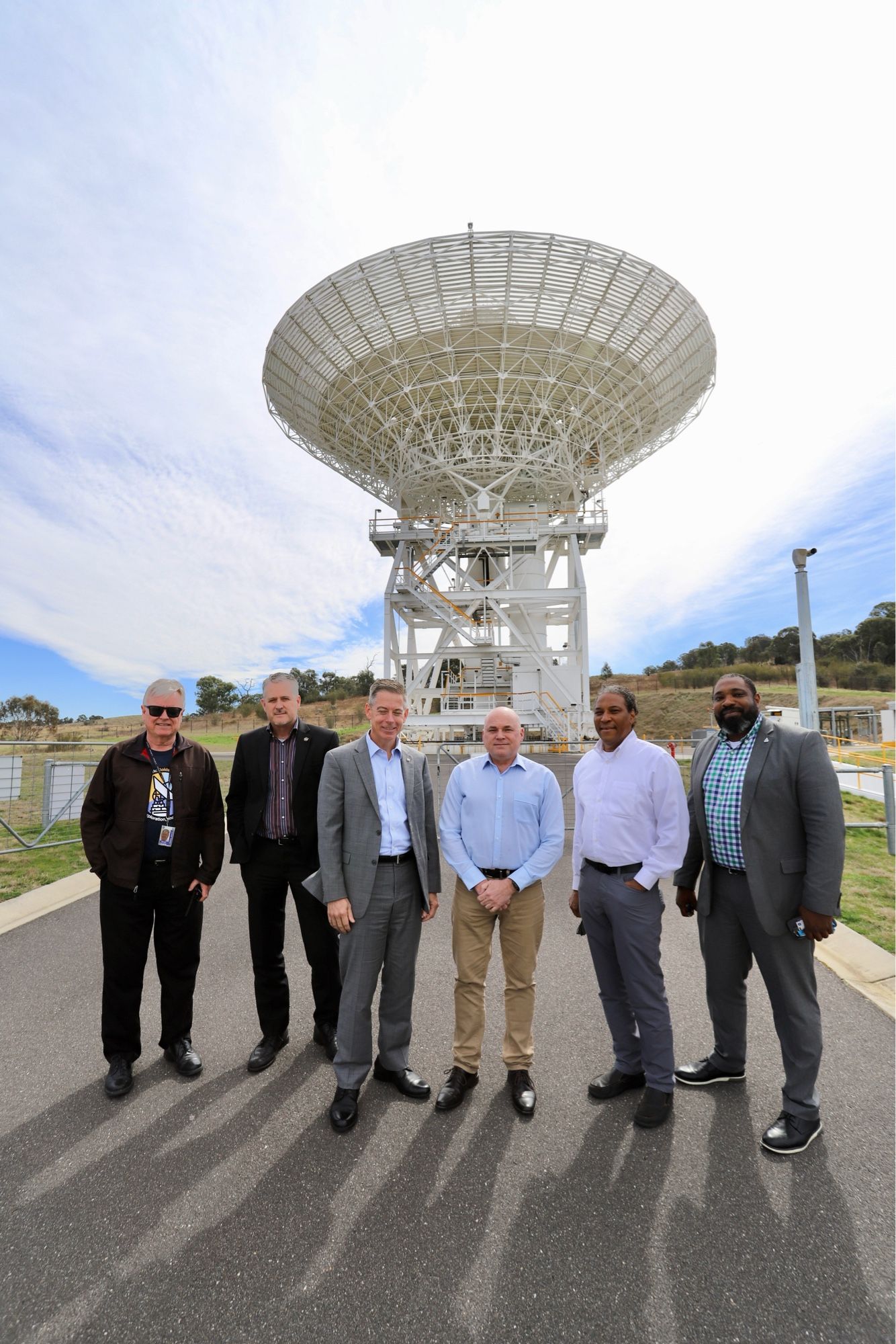 Standing in front of the 34-metre antenna, Deep Space Station 36 are (left to right), Kevin Knights (CDSCC), Greg Mann (NASA), Kevin Coggins (NASA), Kevin Ferguson (CDSCC), Marcus Watkins (NASA) and Philip Baldwin (NASA).