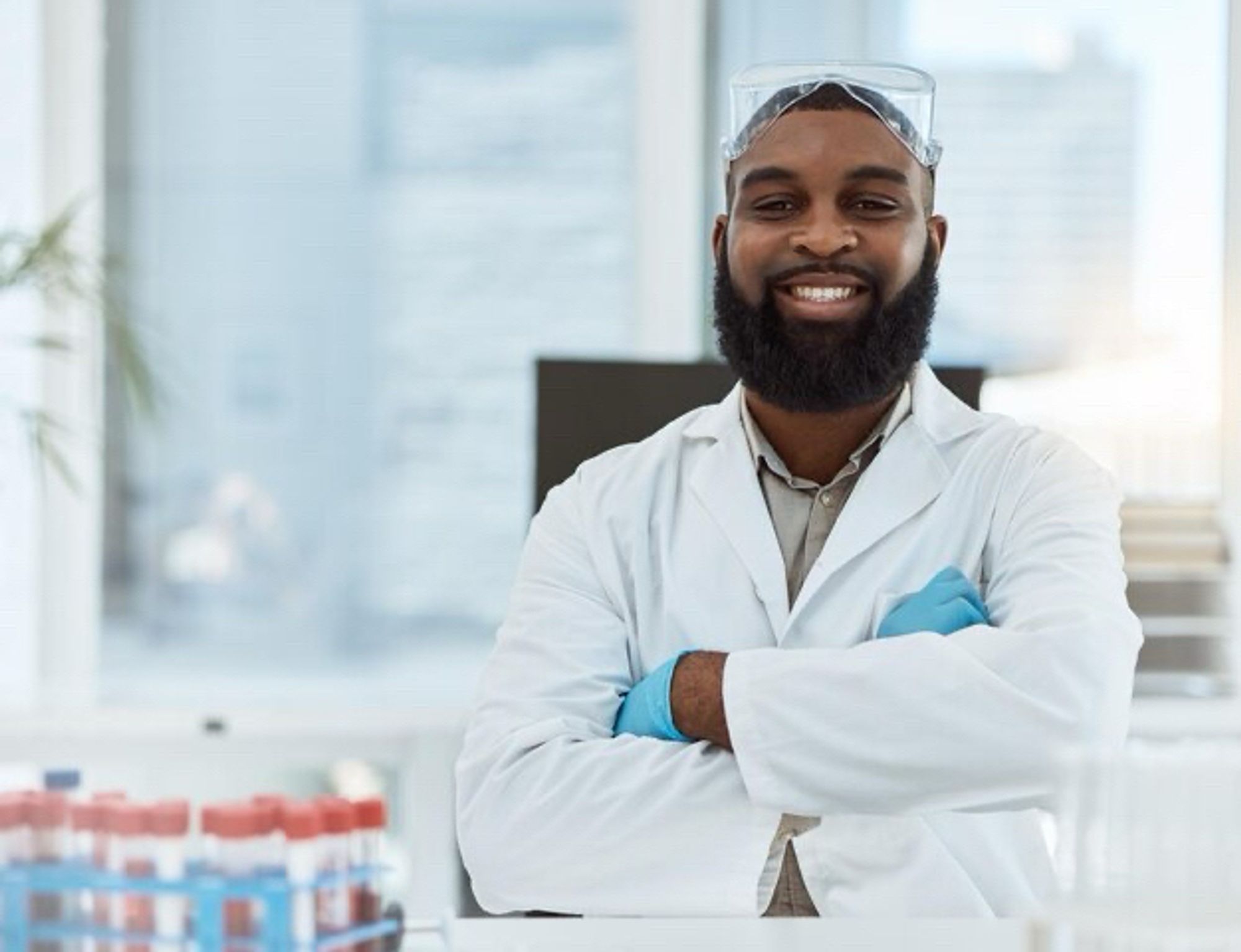 Photographie d’un scientifique noir, les bras croisés, souriant.