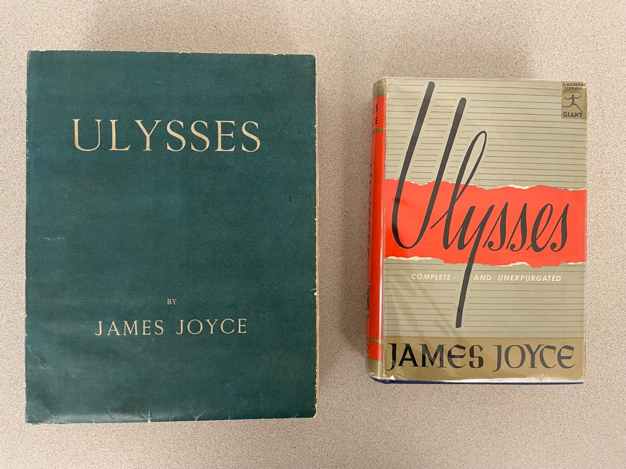 Two copies of James Joyce's Ulysses. Left is the first edition featuring the title and author name on an otherwise spare blue-green background; right is a reprint that features the title in a stylized script with an image of a torn piece of paper in the background.