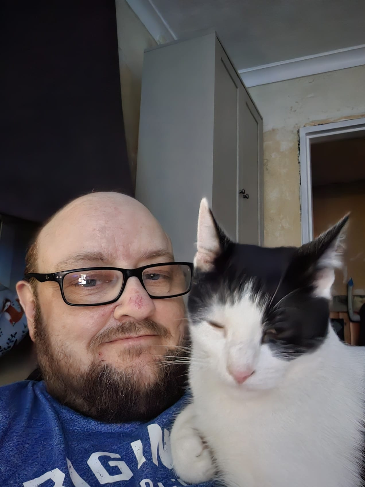 A selfie of my brother-in-law with my shy cat, Mini-Me, cuddled up on his chest.