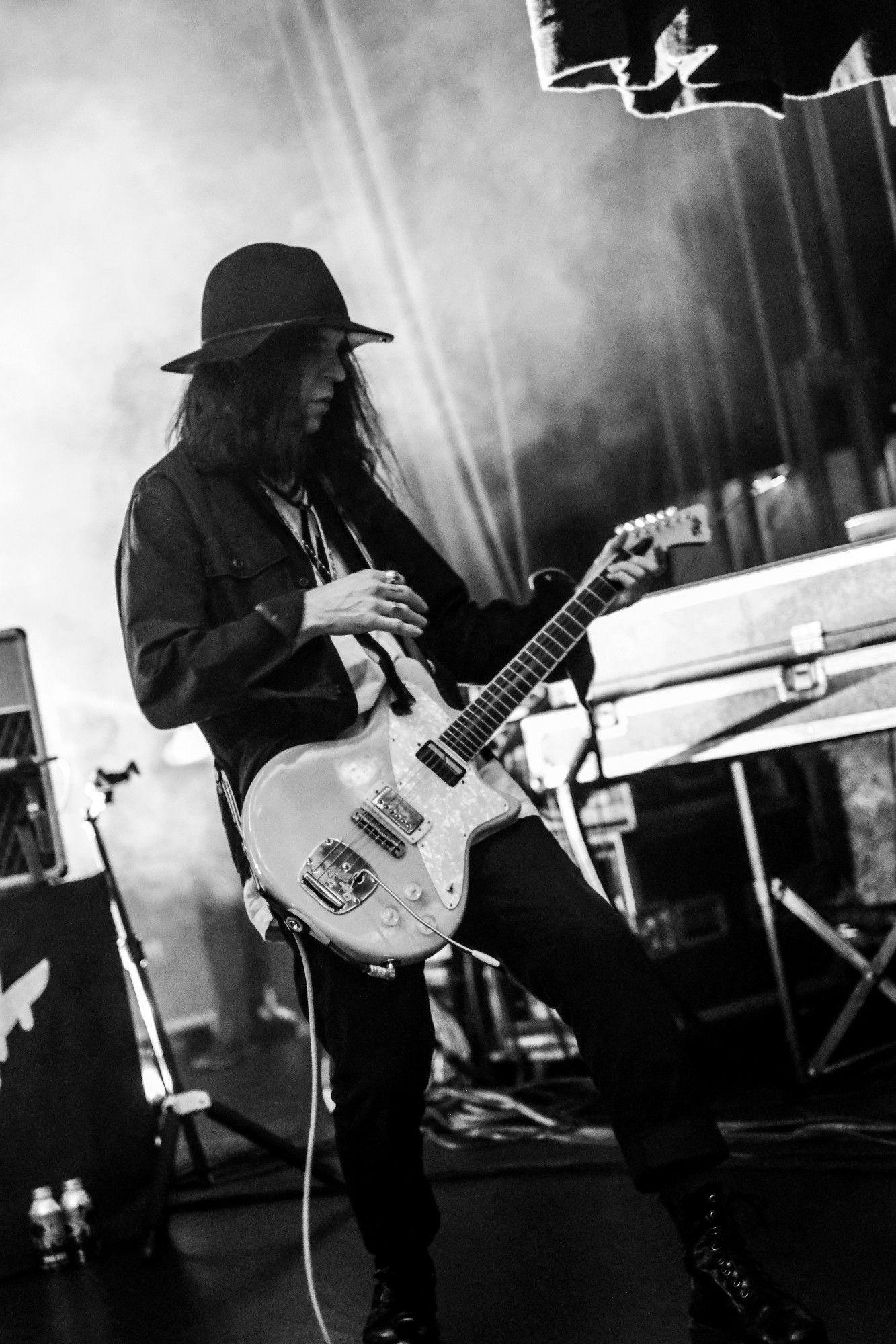 Black and white photo of Peter on stage coming out of the misty shadows with his guitar.