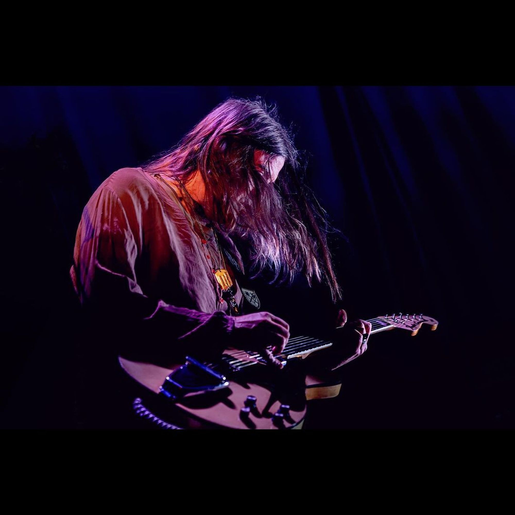 Courtney playing his Fender Coronado guitar, hair cascading in front of his face.