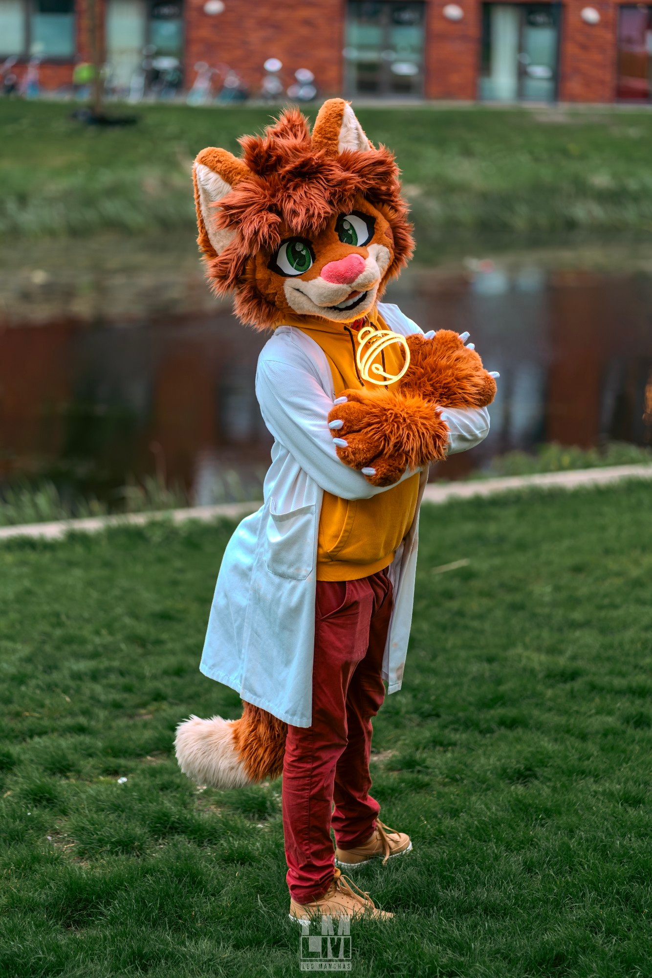 An orange cat fursuiter (Denni) wearing a lab coat and looking at the viewer