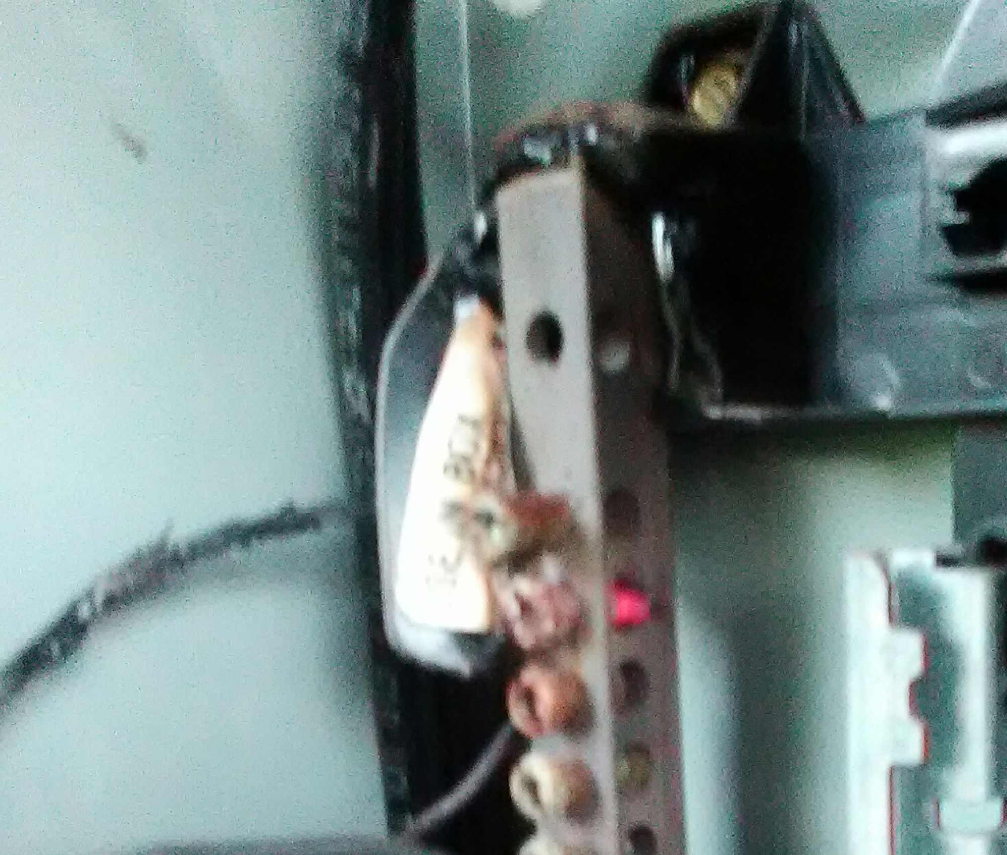 A blurry photo of a bus bar connection where the threads of the 4 bolts are visible through the holes in the side. The second bolt's threads are glowing an enticing yet problematic shade of bright red