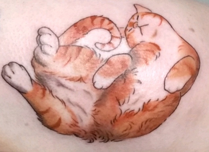 A tattoo on white skin of an orange and white cat. He is depicted belly up, with front paws curled in and hind feet in the air, while his head and his tail meet bend toward each other.