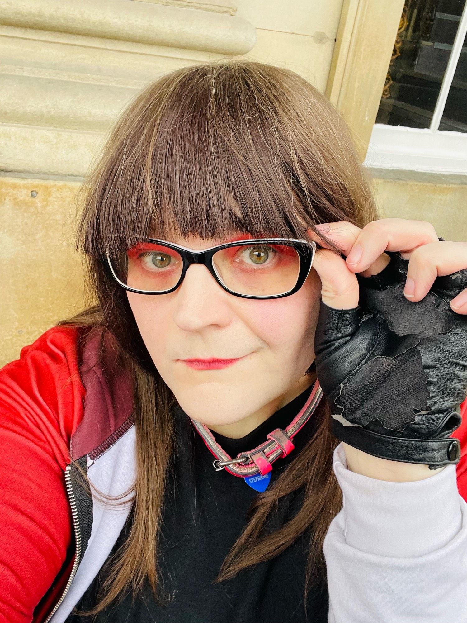 Stephanie selfie: Gori hoodie, red eyeshadow, holding glasses arm with trademark black fingerless gloves.