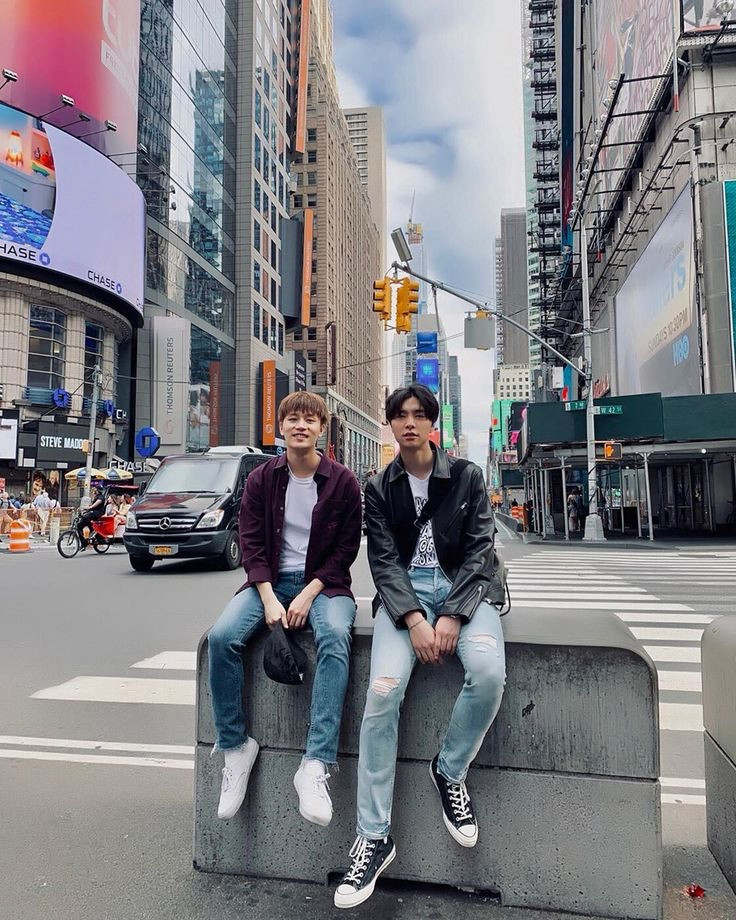 Taeil and Johnny sitting on a cement traffic barrier at an intersection in New York City.