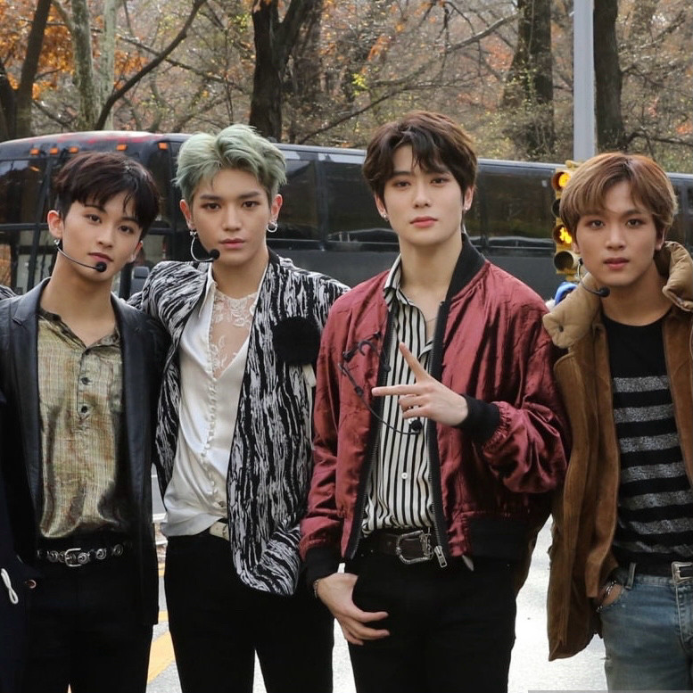 Mark, Taeyong, Jaehyun, and Haechan standing outside with their in-ears and headset mics on, getting ready to perform in the Macy’s Thanksgiving Day Parade.