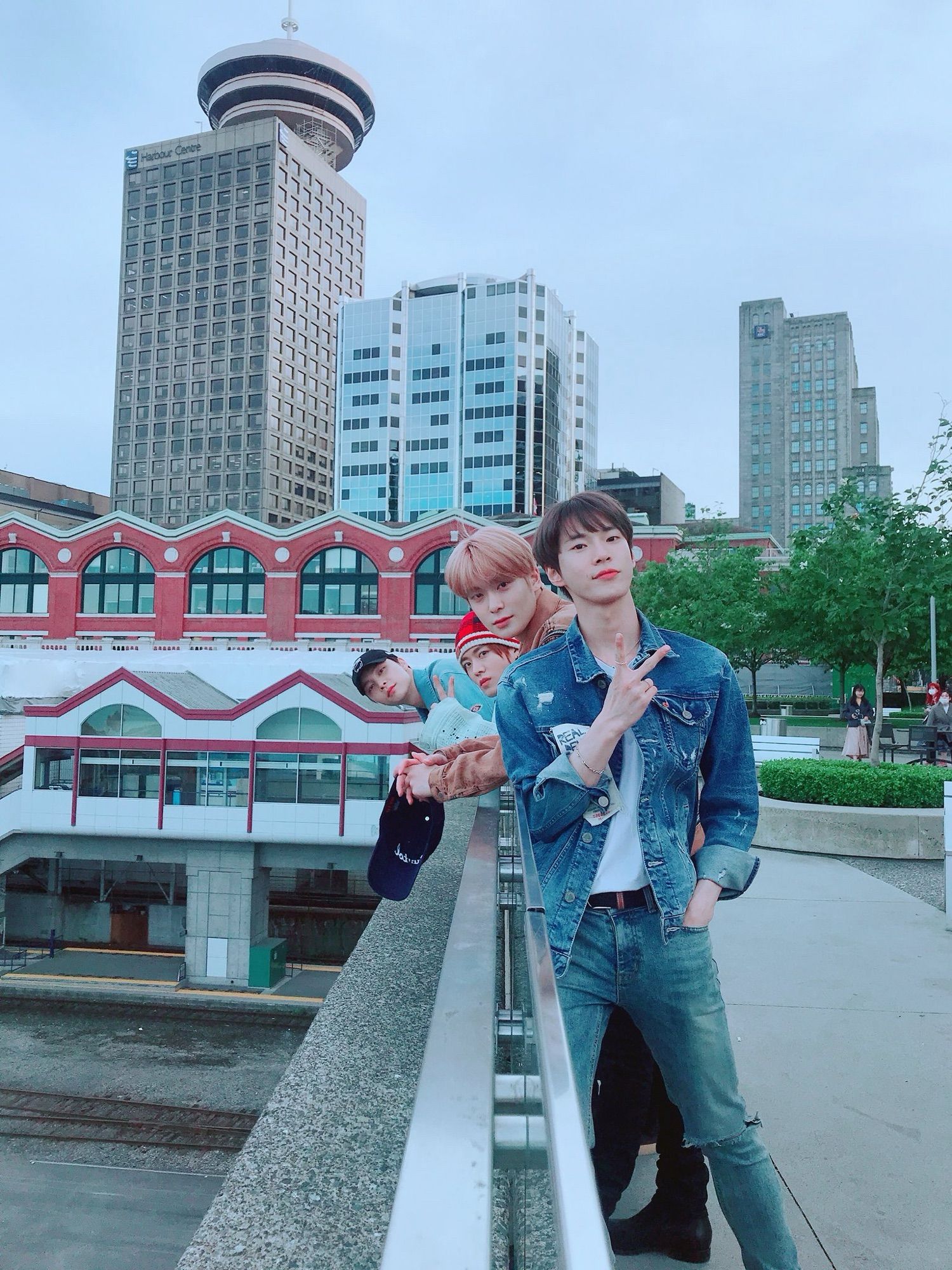 Johnny, Yuta, Jaehyun, and Doyoung leaning against a bridge railing in downtown Vancouver.