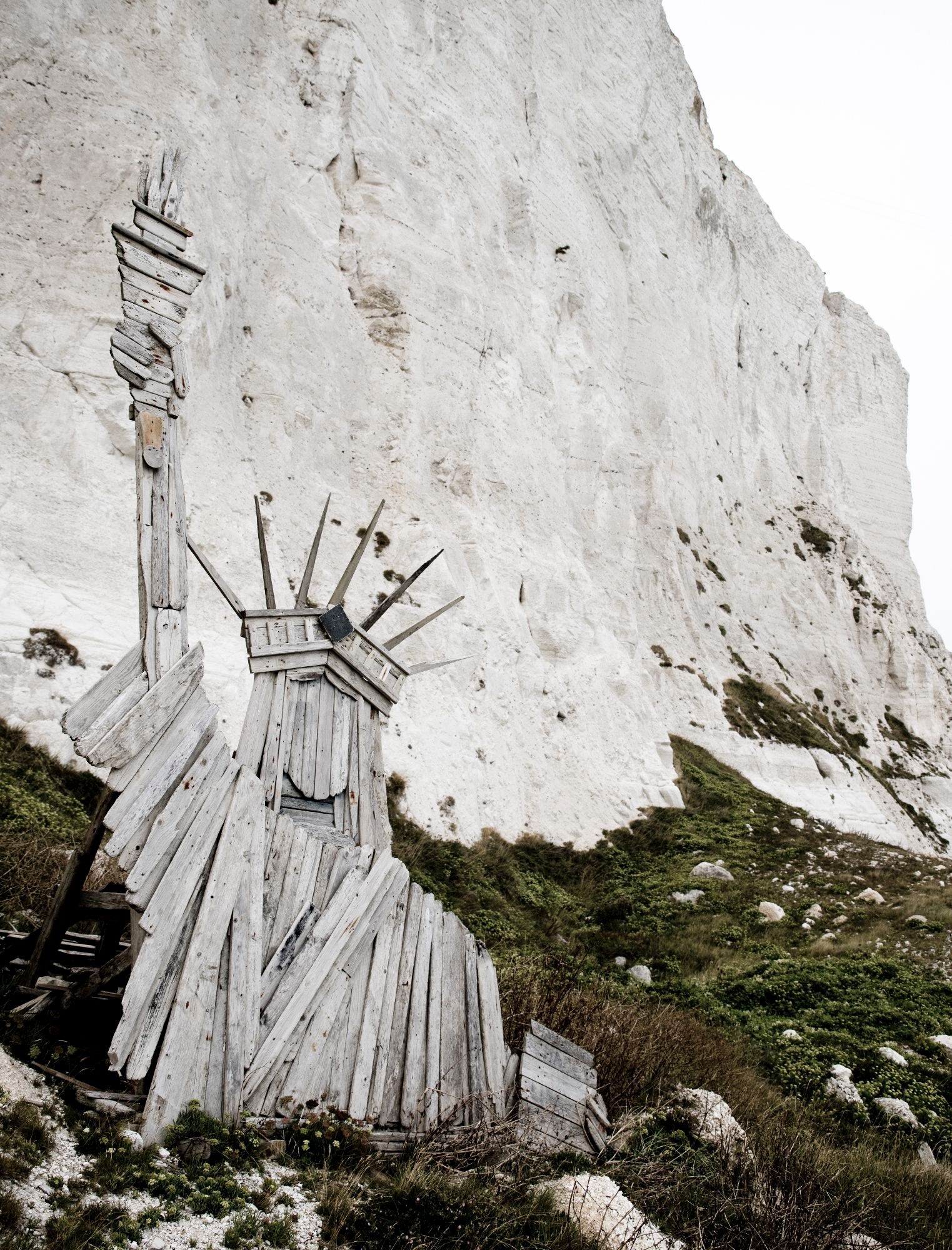 Eine nachgebaute Freiheitsstatue aus Holz vor einer weißen Klippe