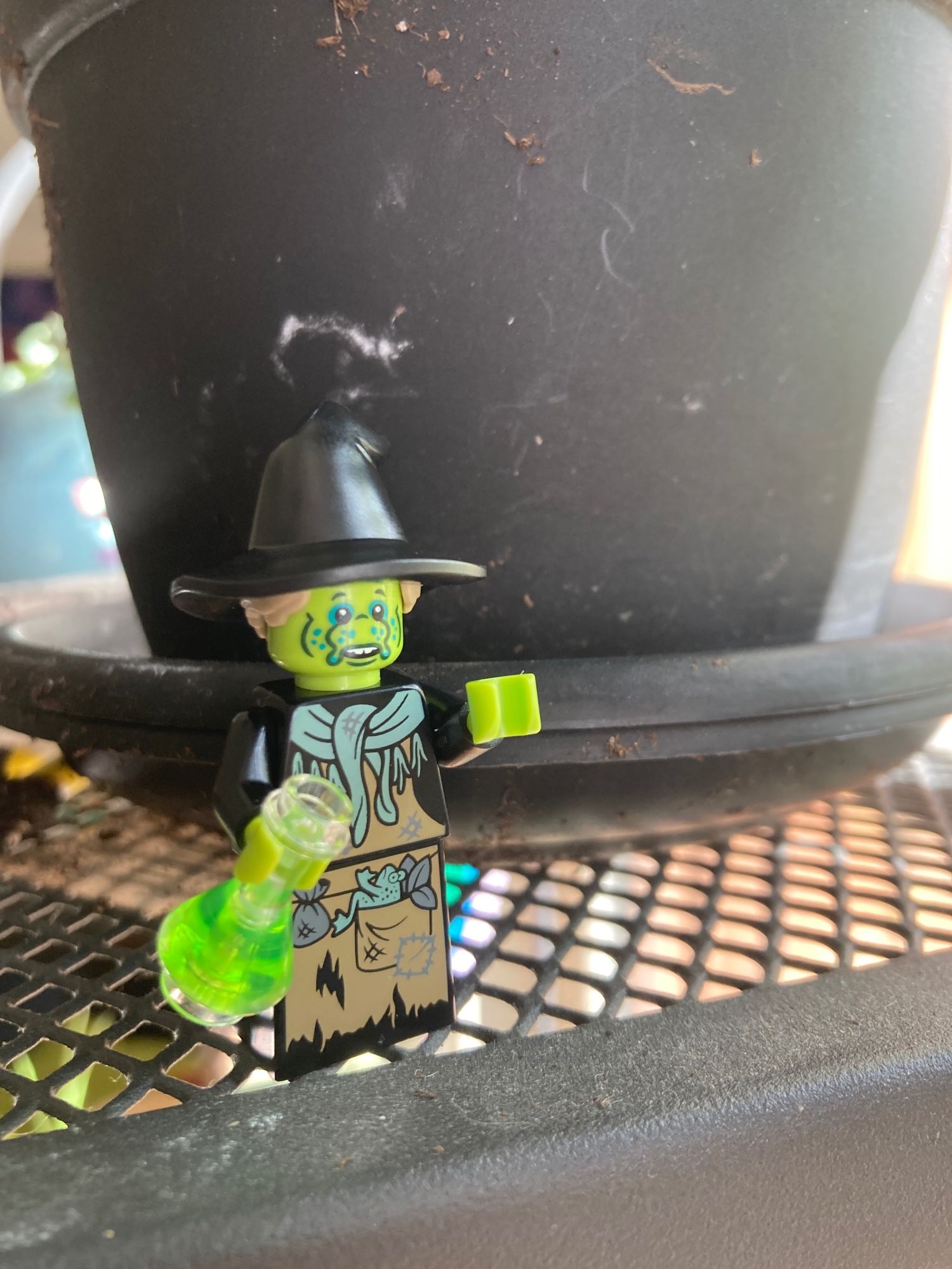 Photo of a lego minifigure: a witch with a slug face, holding a green potion