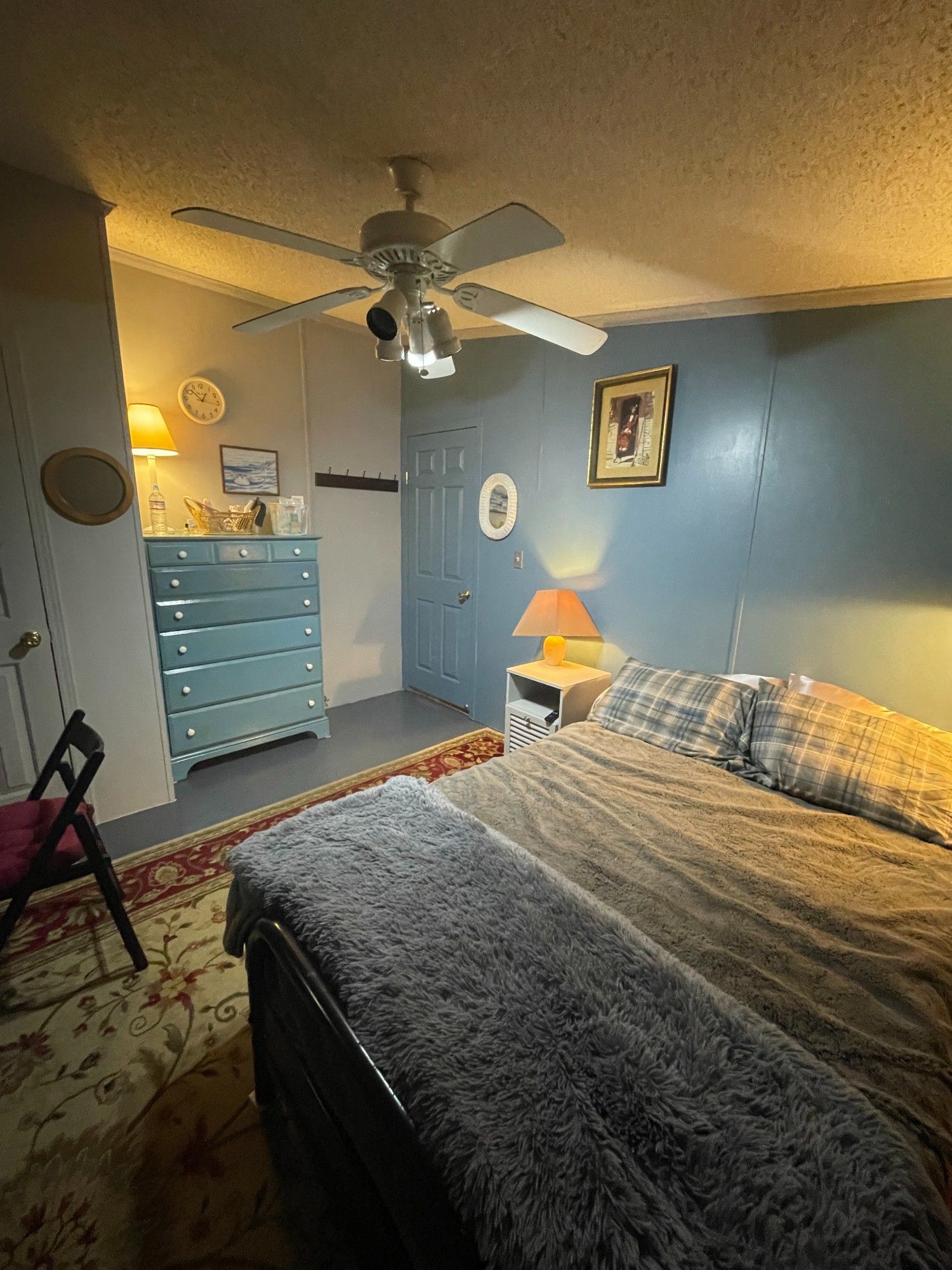 View of my Airbnb room from the corner (where the TV is)... Two-toned walls - union blue & confederate grey. Kidding. But sort of. My mom gave me her lovely area rug - doesn't match, but it's a nice contrast, beige with burgundy & green floral pattern. All the furniture is shades of blue; I painted it all. Lots of light; four lamps & the overhead with the ceiling fan, which WOBBLES on high, to my great distress. I've begged Adam to fix it - he set up all the ceiling fans in my house & they ALL wobble on high. THERE'S my woe for Wednesday. I HATE IT! Anyway - full-sized futon bed - TWO futons, super comfy. Furry blankets. You can't see it, but one of the pictures on the wall is of my late father in his kilt, looking cheeky. (heh.) On the bureau, bottled water, a basket of toiletries, and a basket of foodstuffs in case the guest is hungry after her travels. Bedside table is the same shade of grey as the walls - I painted that in a hurry yesterday, after buying it at the ReStore. YIKES!😳