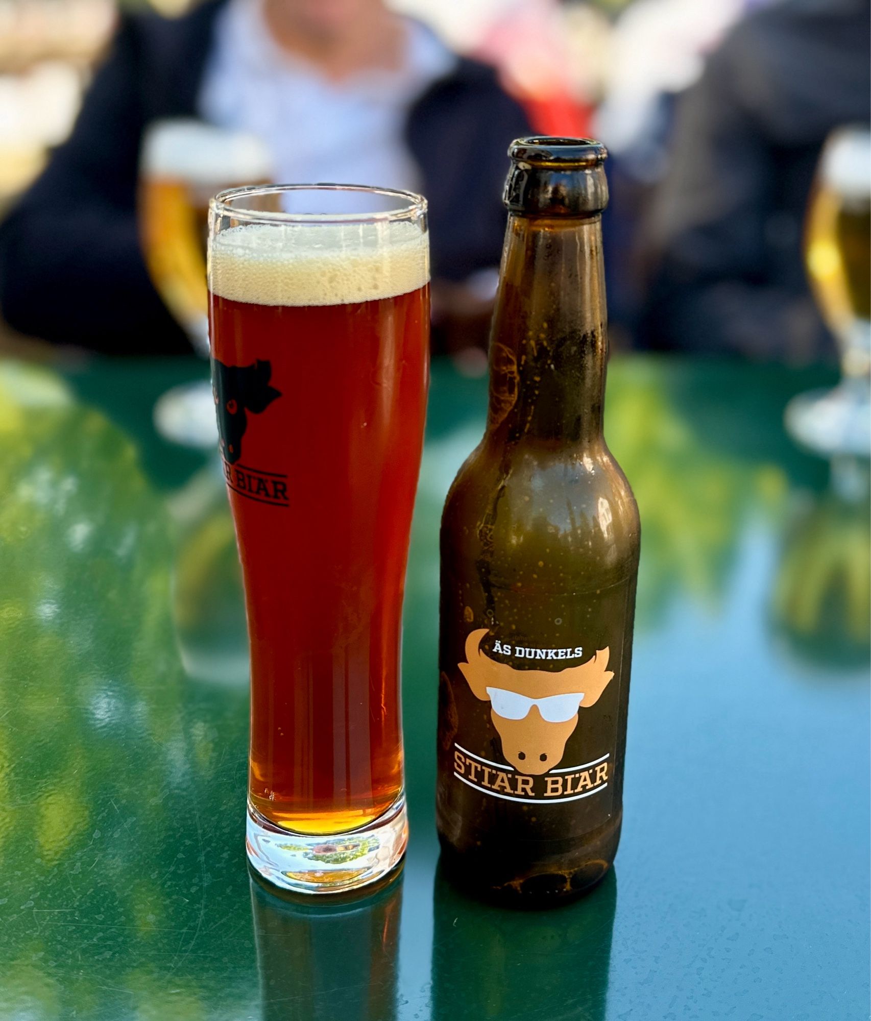 Ein dunkles Bier im schlanken Glas, daneben die Flasche «Stierä Biär»