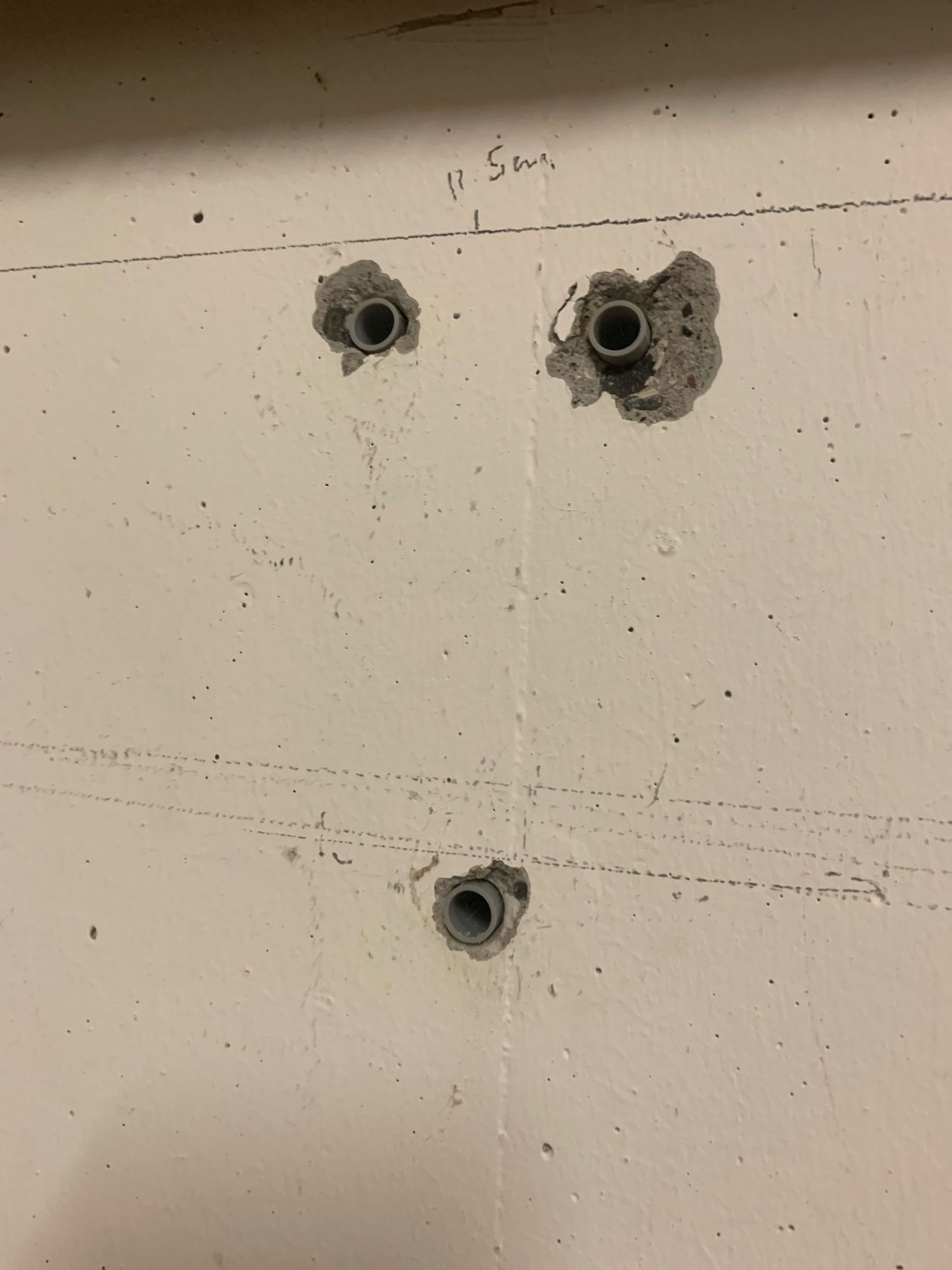 three holes drilled in the cement wall form a face, with eyes at the top and a small open mouth at the bottom.  this one looks like he is suffering from a migraine, with the left eye much larger than the other