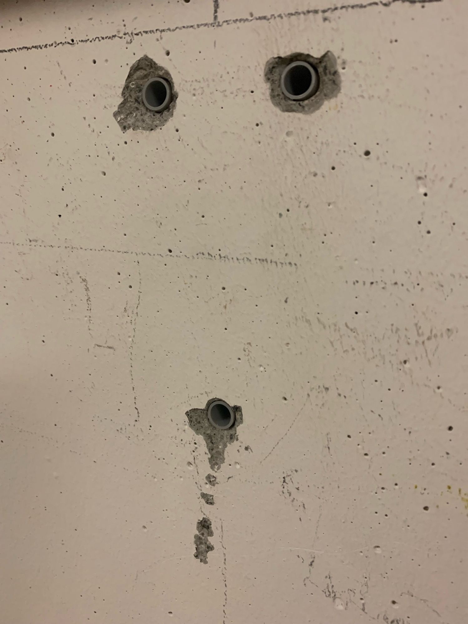 three holes drilled in the cement wall form a face, with eyes at the top and a small open mouth at the bottom.  this one has a little beard tied in knots hanging off his chin