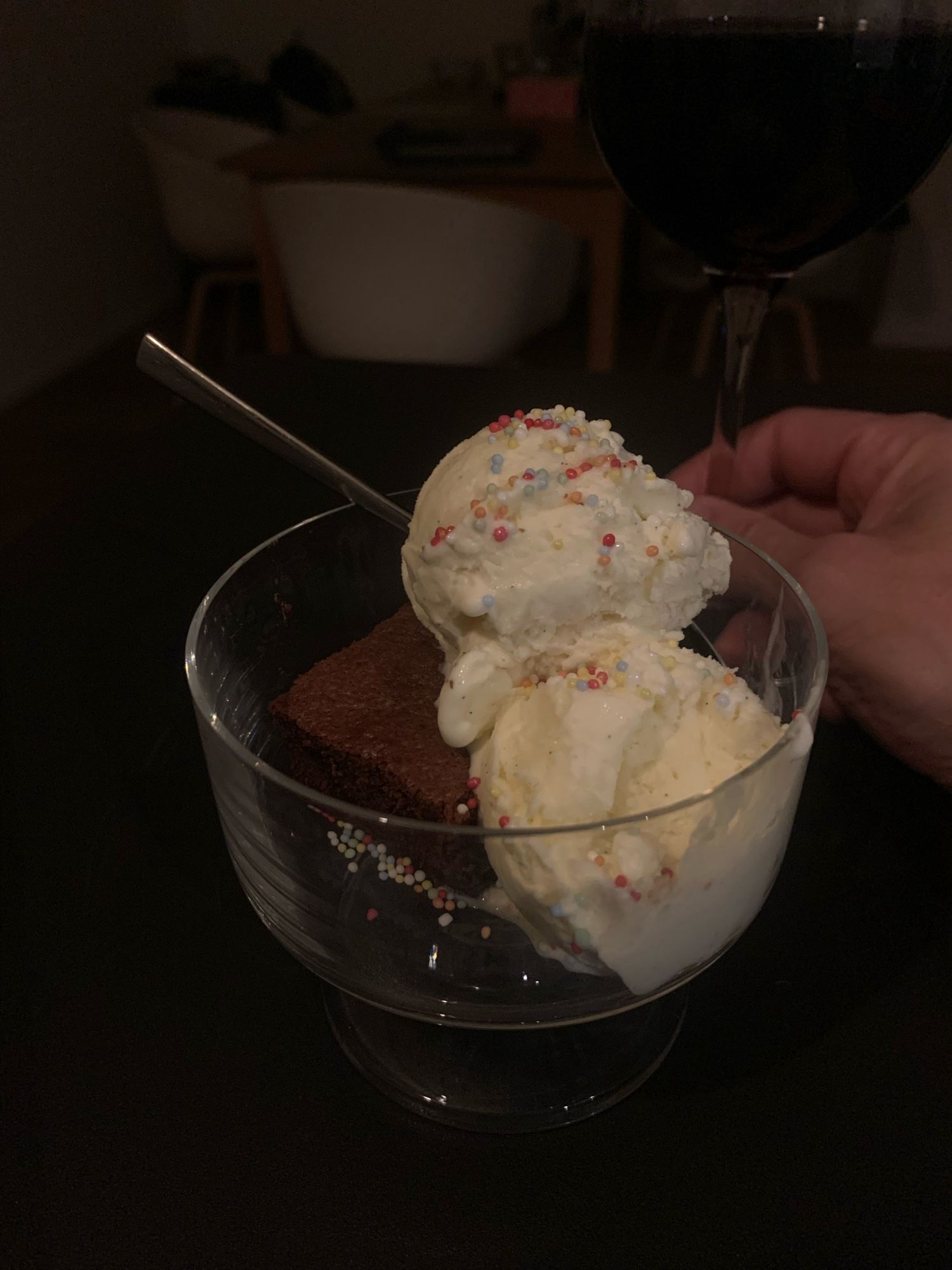 a square of hot brownie with two dollops of vanilla ice cream, topped with hundreds & thousands.  A pint of wine is visible in the background, which is for me