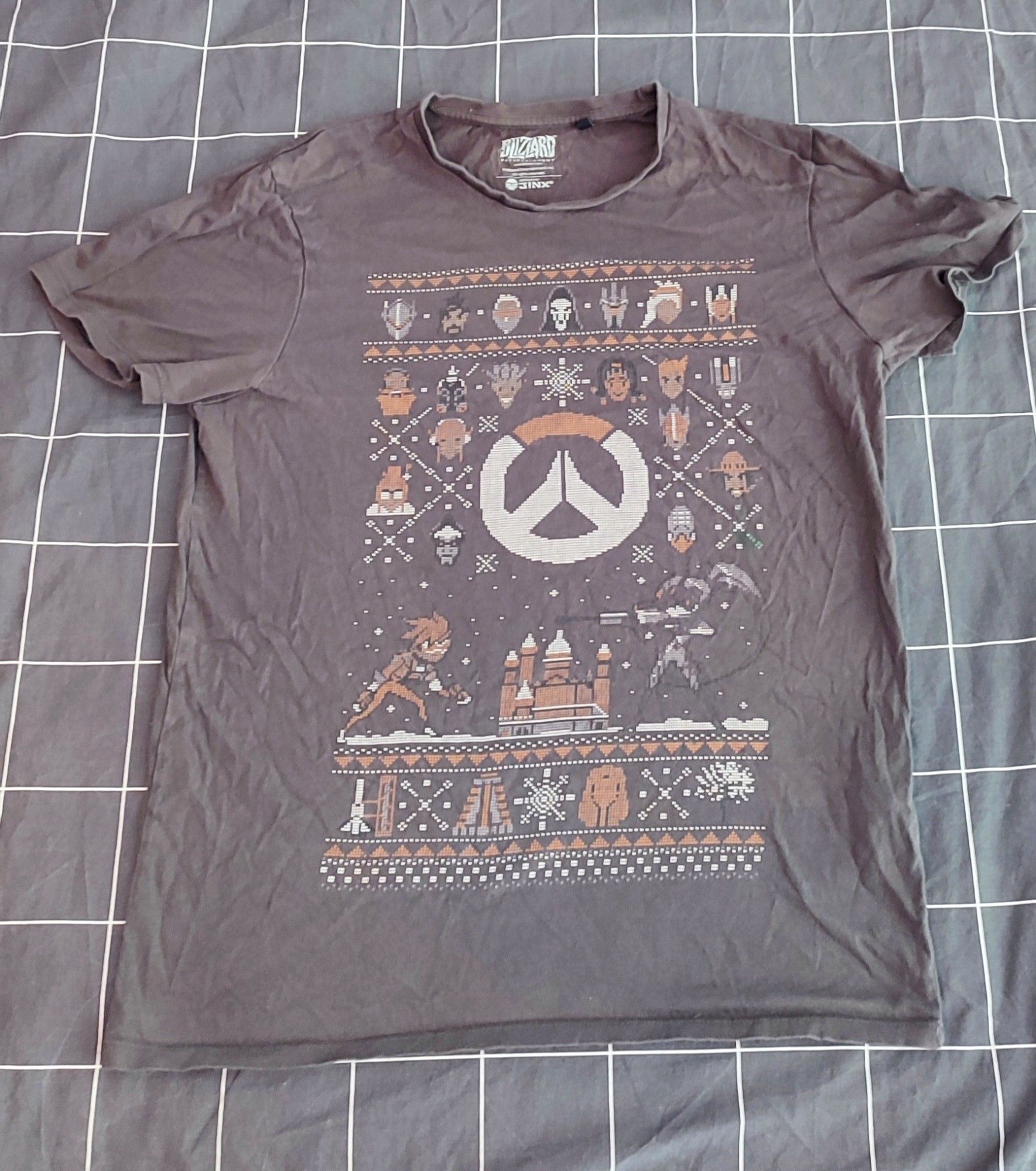 Ein braunes Shirt mit Aufdruck in Weiß und Orange von Overwatch im Weihnachts-Muster.
Größe M (Hersteller Blizzard)