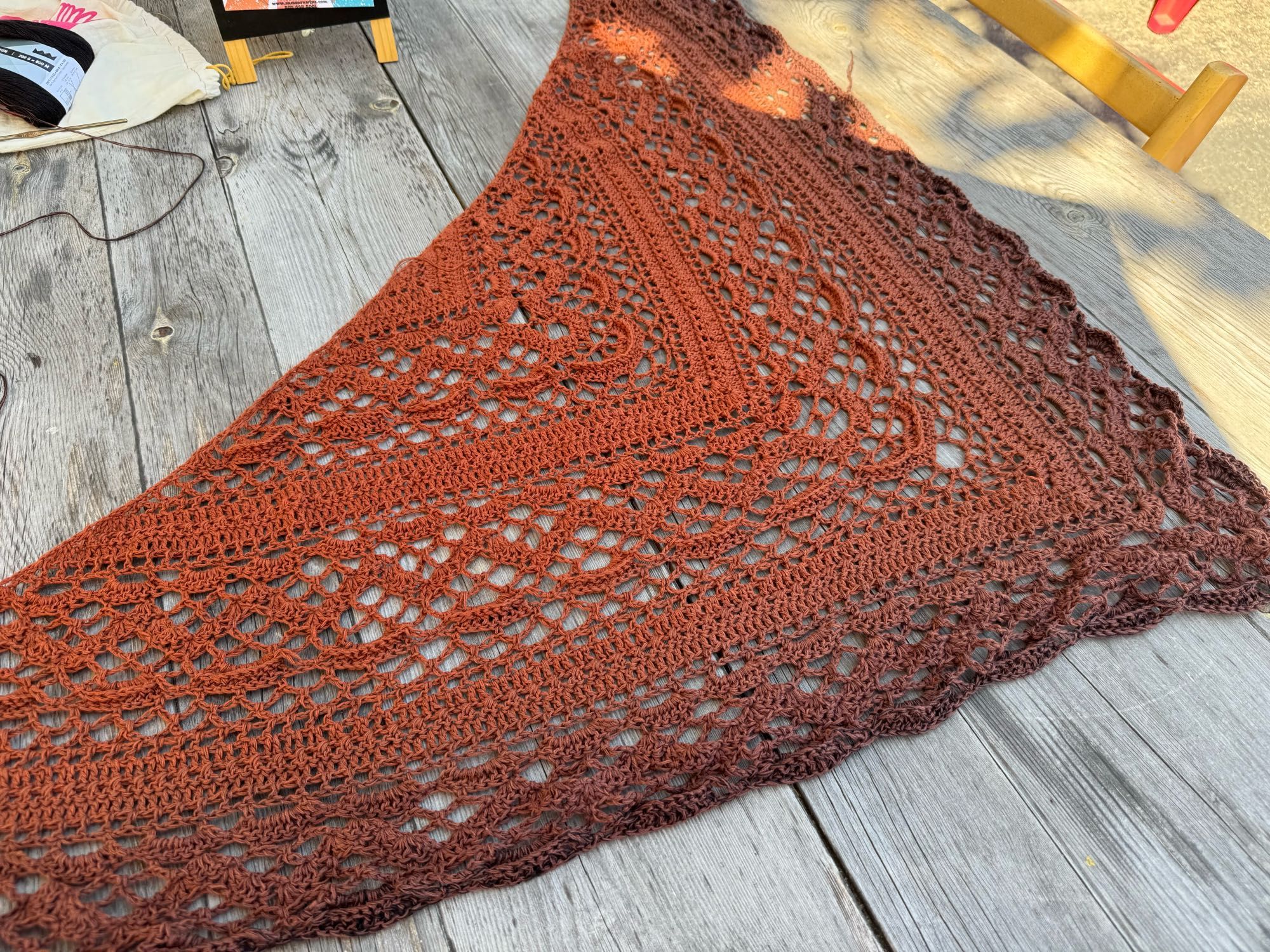 Curry colored shawl spread out on a grey weathered wood table.