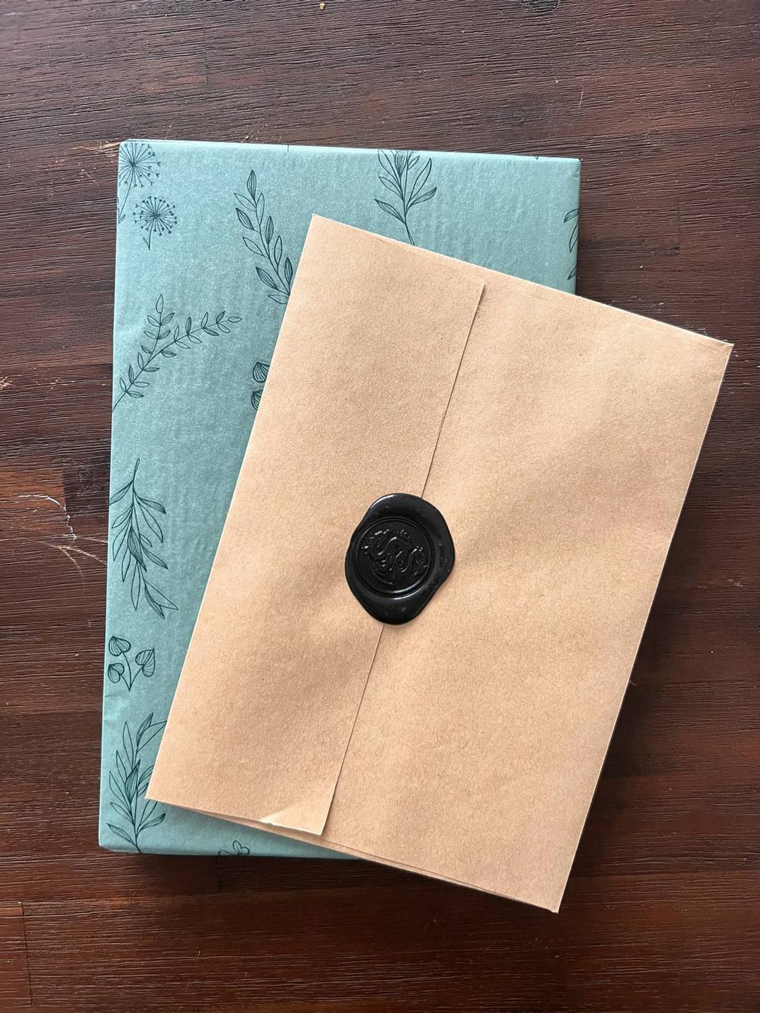 Photo of a book wrapped in green paper and a brown paper letter envelope.