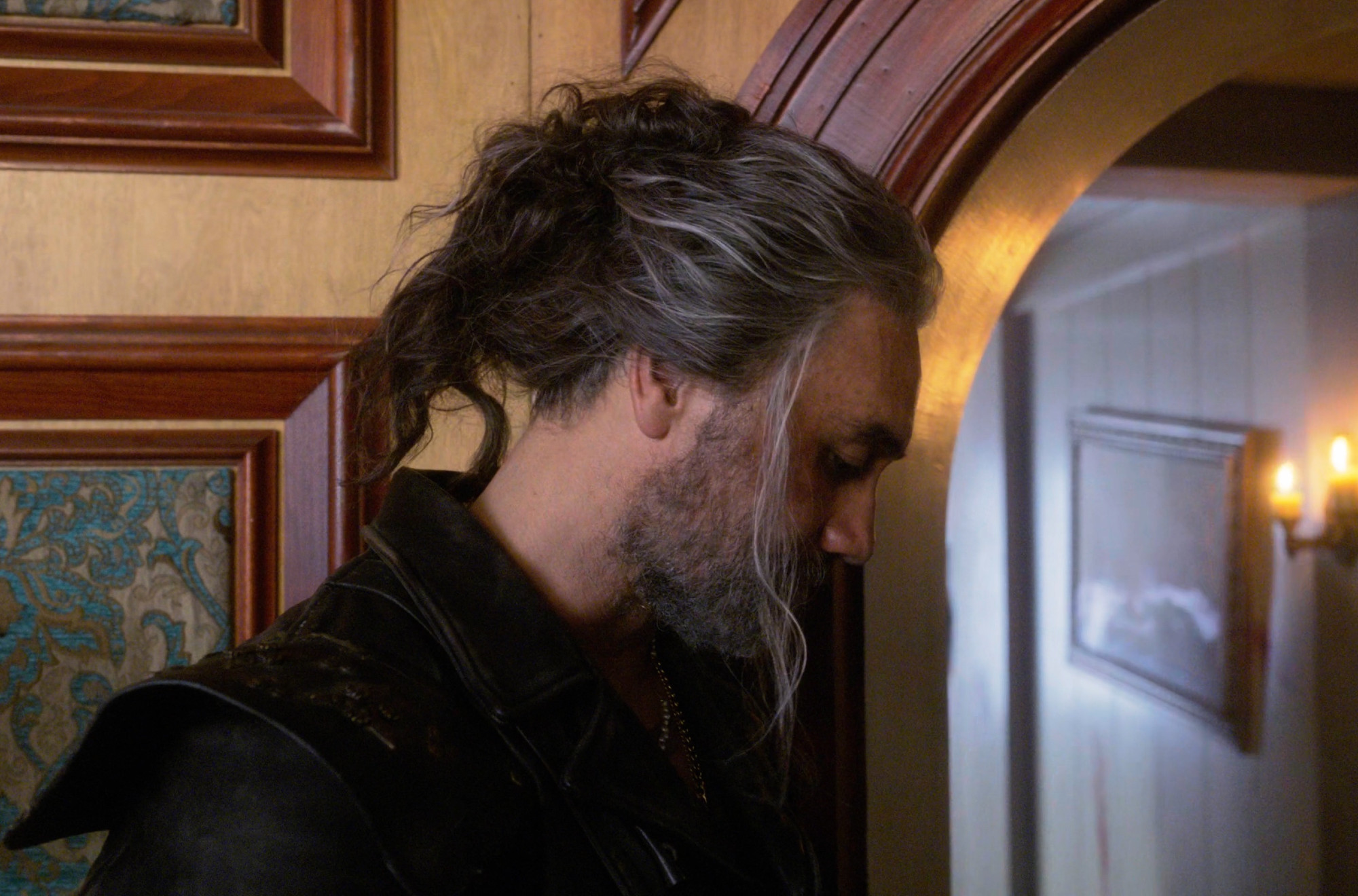 ed teach in the captain's cabin with the messy bun, standing by the door turned away showing him in profile (our flag means death s2e2)