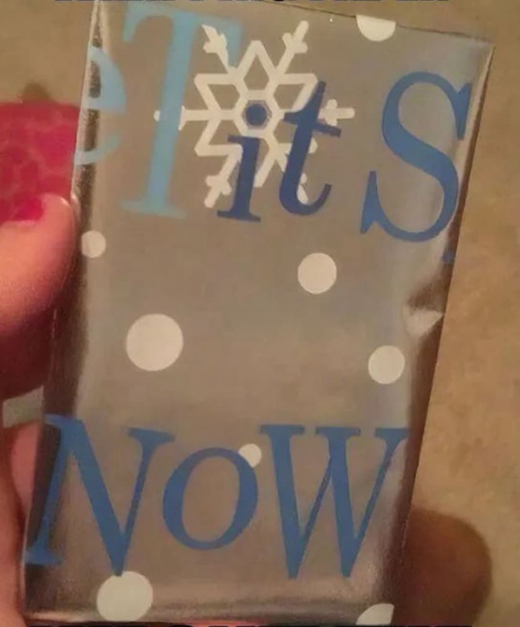 A Christmas present wrapped in wrapping paper that says "tits now". Originally, it said "let it snow", but it became "tits now" due to the way it landed on a side of the package