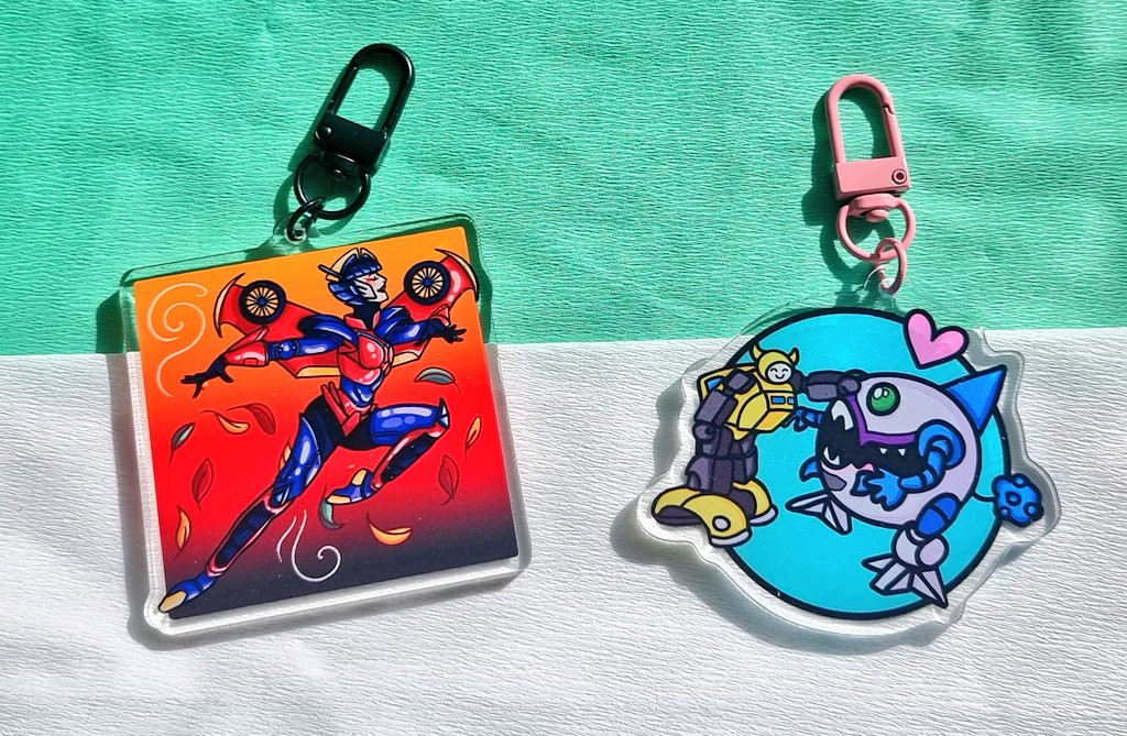 Acrylic keychains depiction Transformers Characters: Windblade dancing like a ballet dancer in the style of George Petty 1950s pinups, and Bumblebee petting Gnaw the Sharkticon with a loveheart above them - they're friends! 

Both are colourful and vibrant, with a playful style.