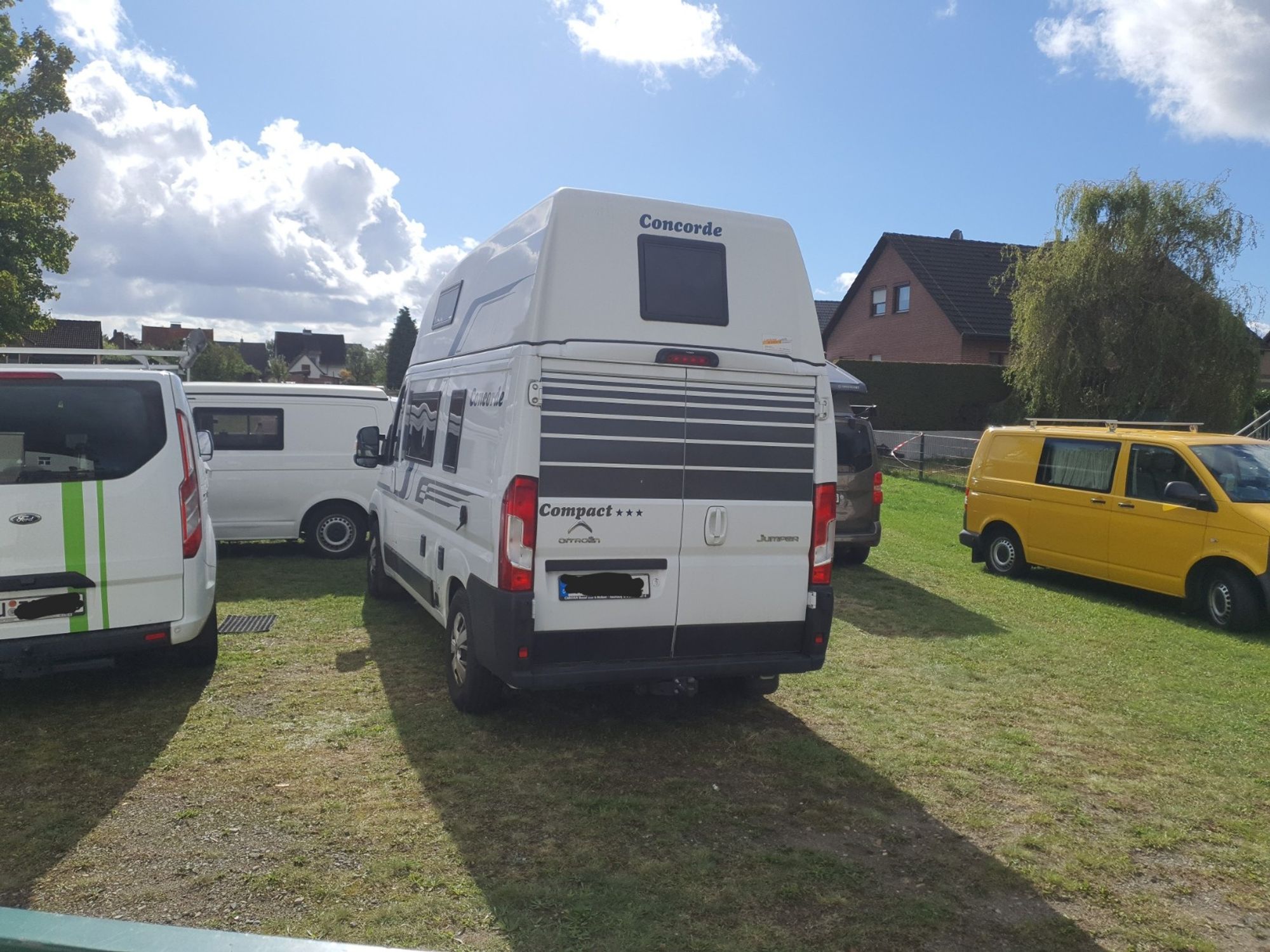 Mehrere Campingmobile stehen zusammen auf einer Wiese