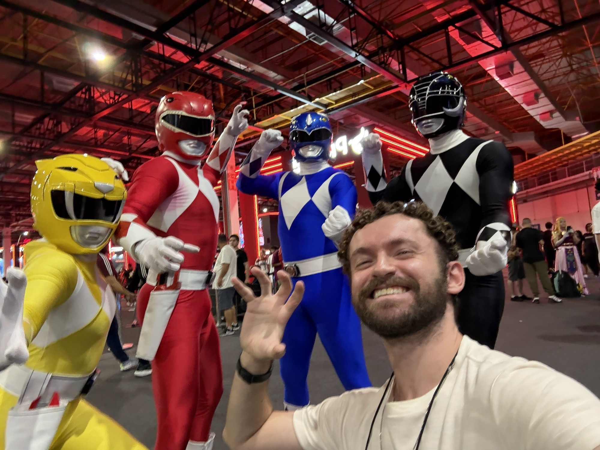 Um adulto de quase 30 anos tirando foto com os Power Rangers vermelho, azul, amarelo e preto durante a Brasil Game Show em São Paulo