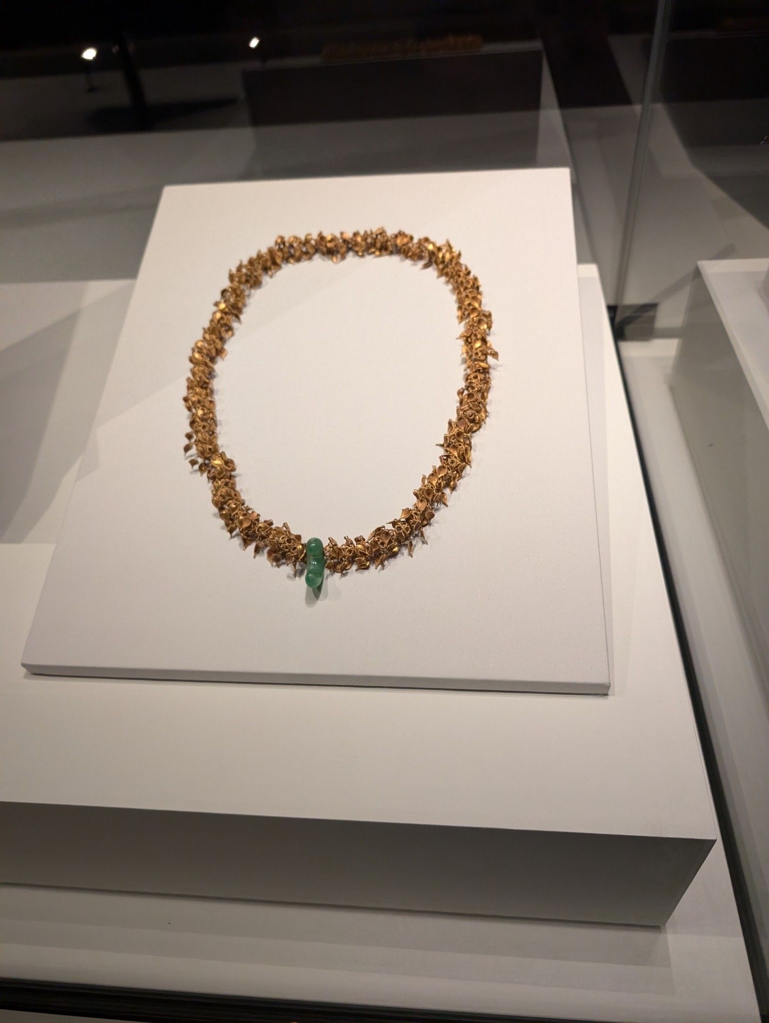 Spectacular gold jewellery have been excavated from burial grounds in Silla dating from the late AD 300s to the first half of the 500s. These artefacts show a close connection between gold and power. The mysterious 'comma-shaped' jade ornament, an ancient form, appears to have been exclusively used by peoples of the Korean peninsula and the Japanese archipelago during this period. Picture of large gold necklace made of hundreds of small leaves of gold with a jade pendant.