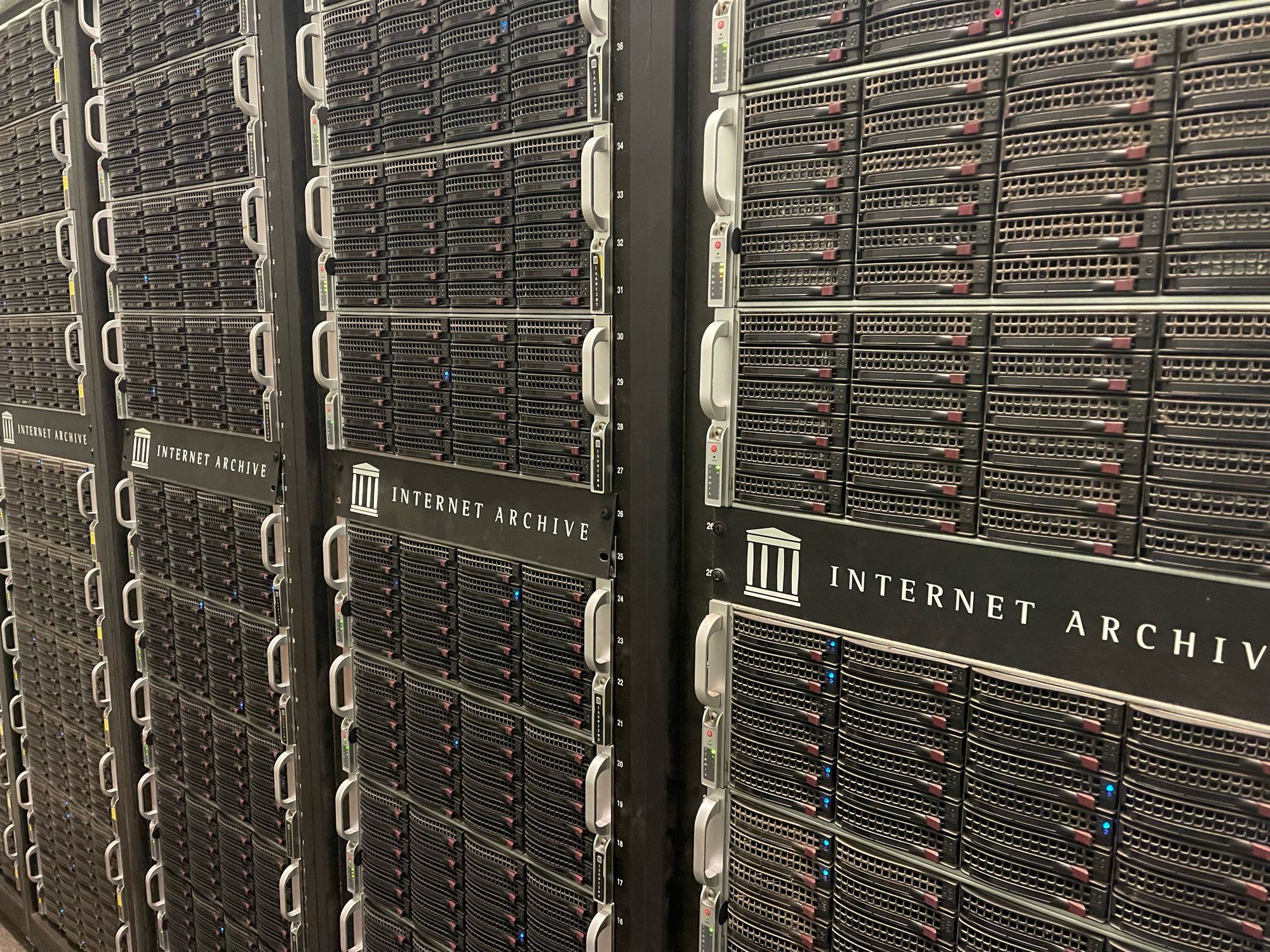 Four racks of black 4U servers of the Internet Archive. Each server hold 36 disc drives (24 in front, 12 in back) and each rack can hold 5.5 petabytes (post ZFS error correction). The server chassis are manufactured by SuperMicro.