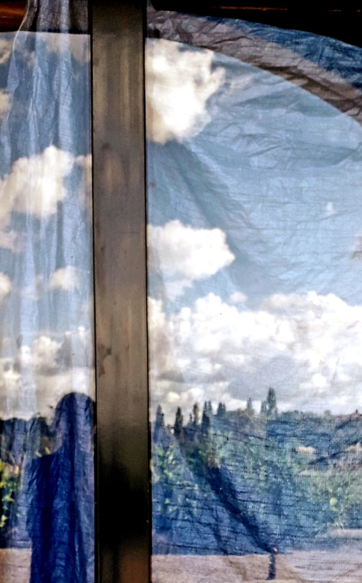 Reflet dans une vitrine. Paysage et personne et nuages