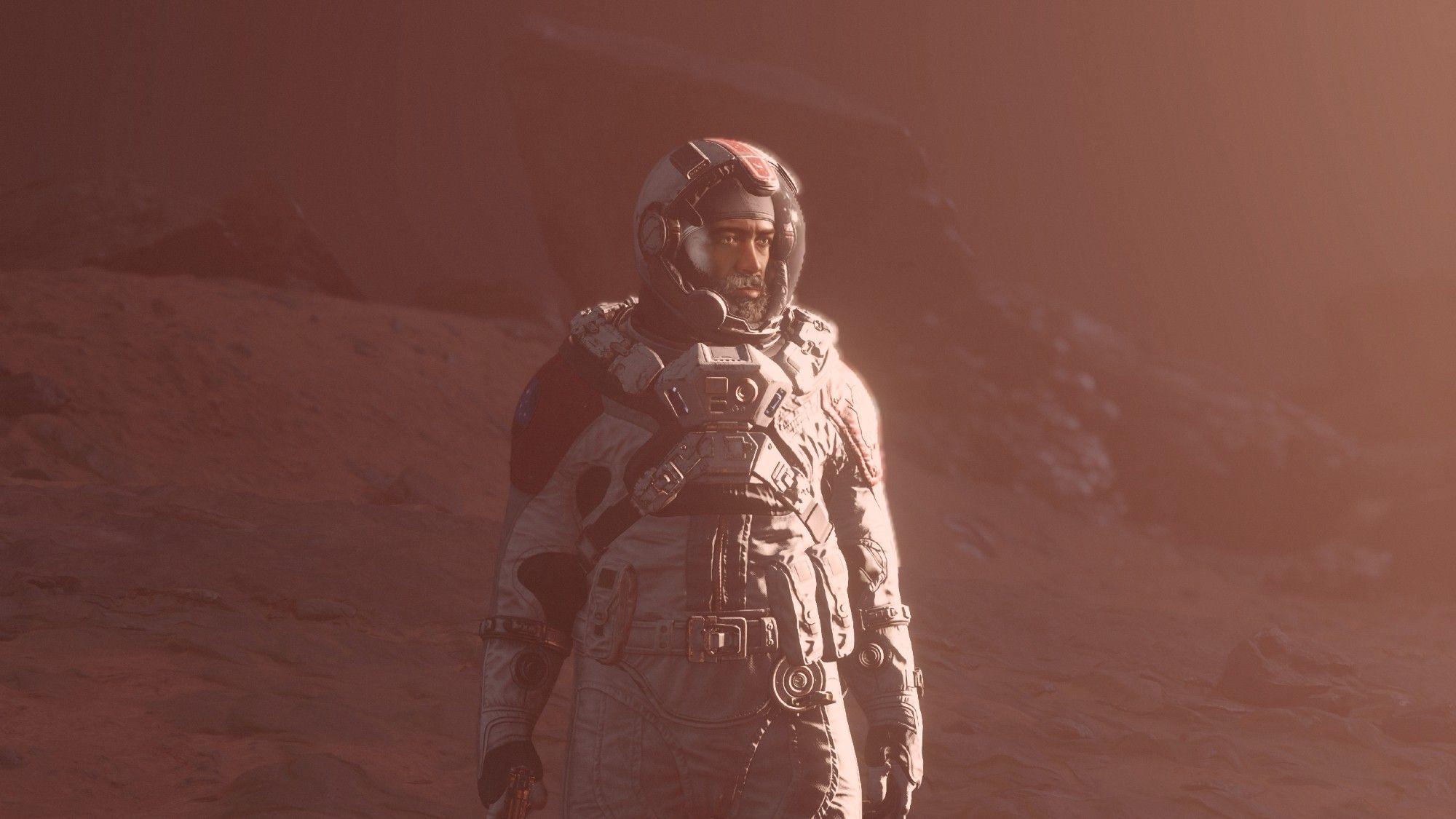 A screenshot from the video game Starfield. A character in a space suit standing behind a formation of rocks.