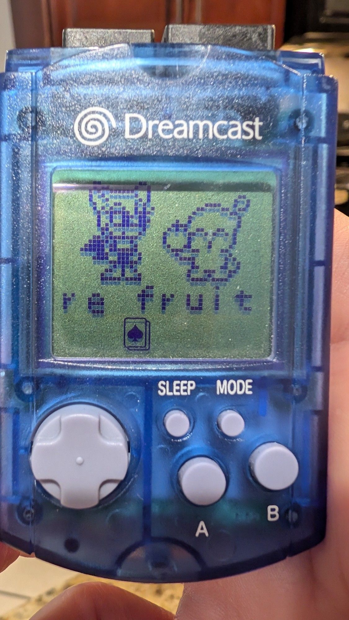 A clear blue Dreamcast VMU displaying Rouge the Bat and a Chao receiving a fruit