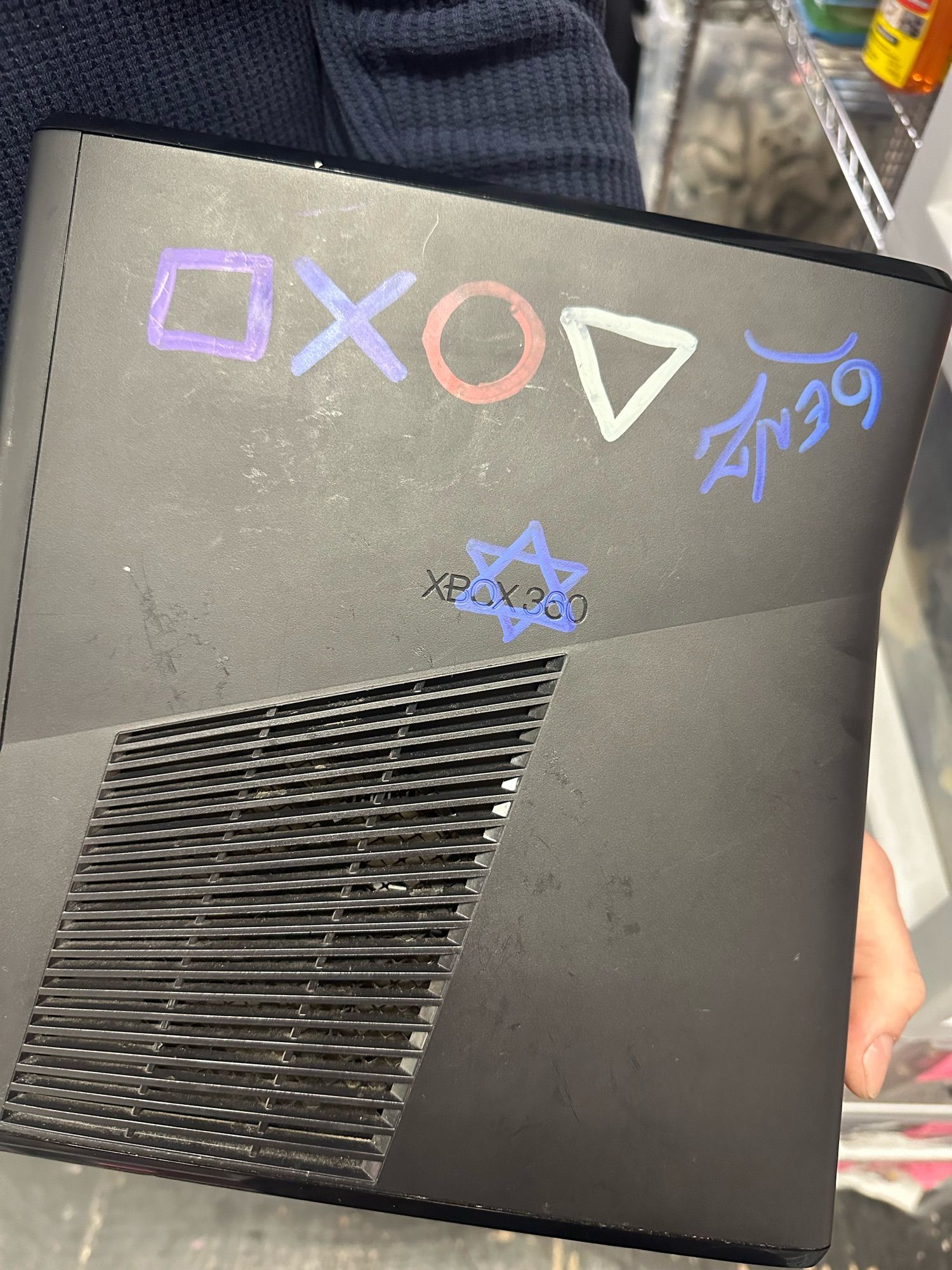 An Xbox 360 with PlayStation symbols painted on it and also a blue Star of David for some reason