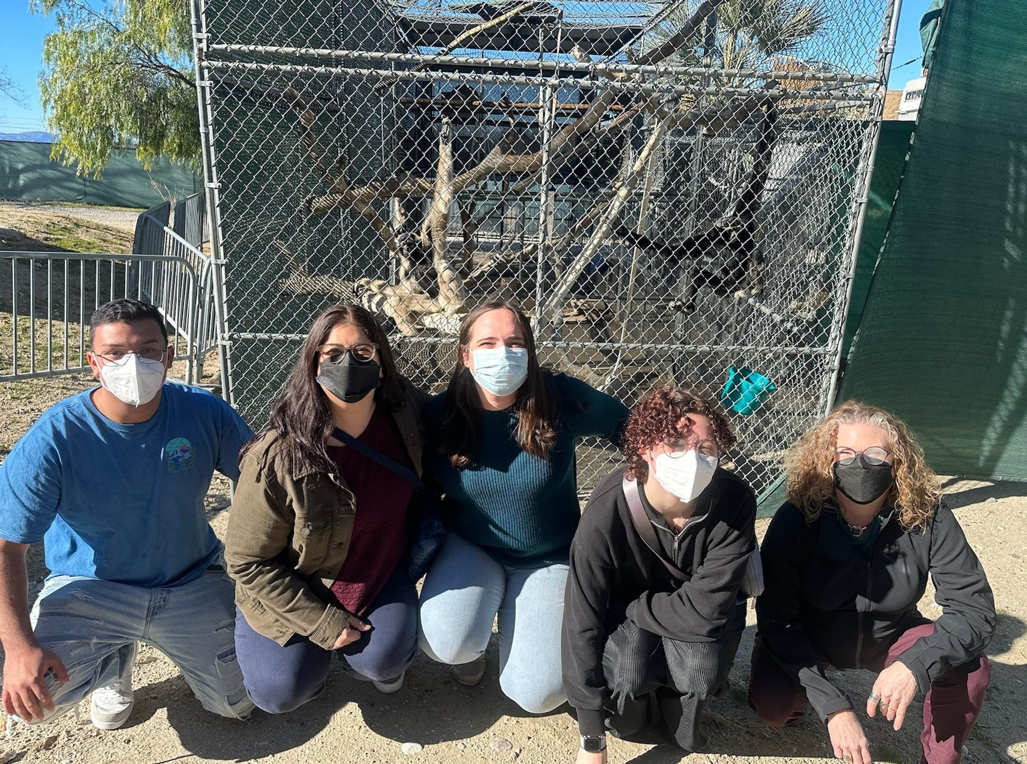 5 O'Neill lab members in front of two relaxed gibbons