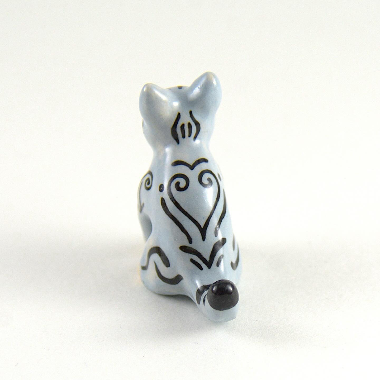 The back view of the small ceramic cat. This view shows a heart pattern painted in the tabby stripes.