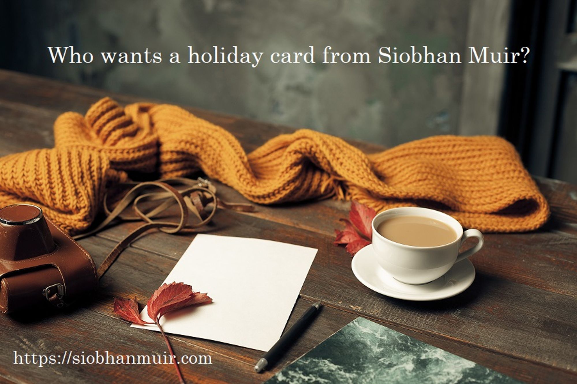 Text: Who wants a holiday card from Siobhan Muir?
https://siobhanmuir.com
Image: Orange knitted scarf behind a leather camera case, a cup of coffee on a saucer, and a pen and paper on a wooden table. Red leaves provide color accents.