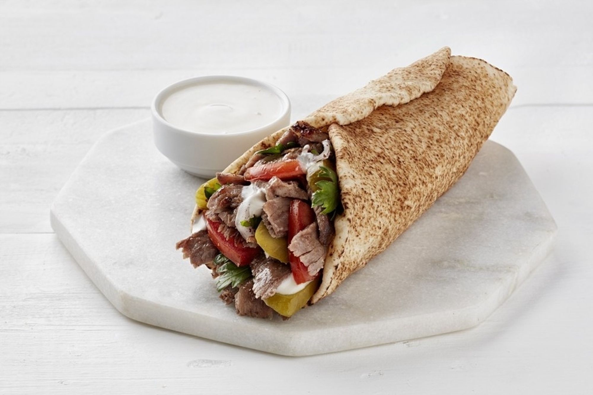 an image depicting a shawarma on a white stone plate