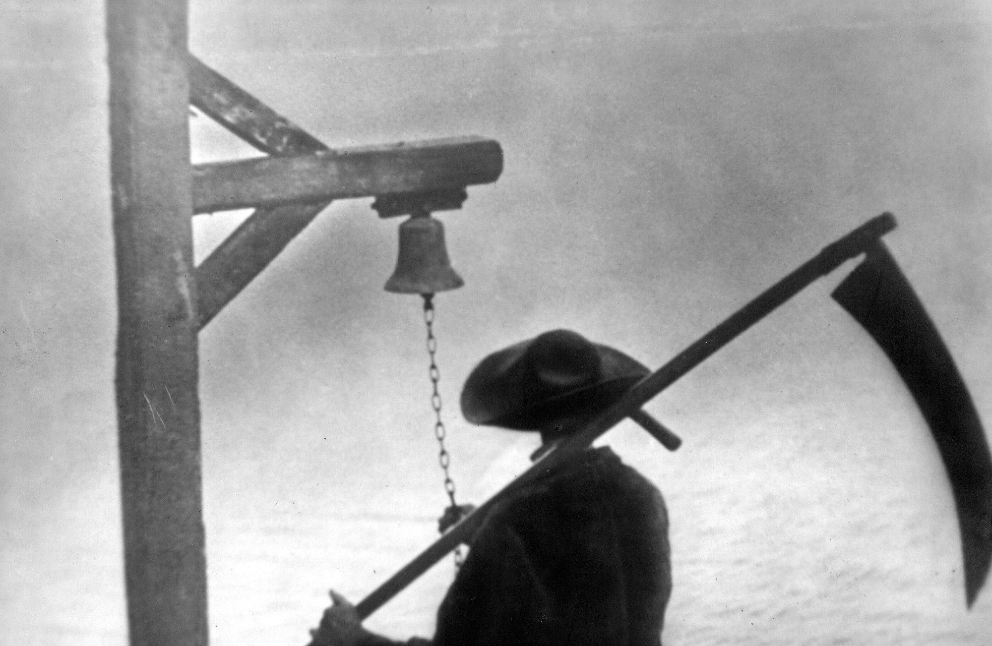 A man with a scythe has his back to the camera. He stares out at a river, the opposite side shrouded in fog. The enigmatic figure ring is ringing a bell that's hung from a post by the river. He is not explicitly Charon or the Grim Reaper, but one can't help but think that he's the image of some greater power, an embodiment of death or a guide for departed souls.