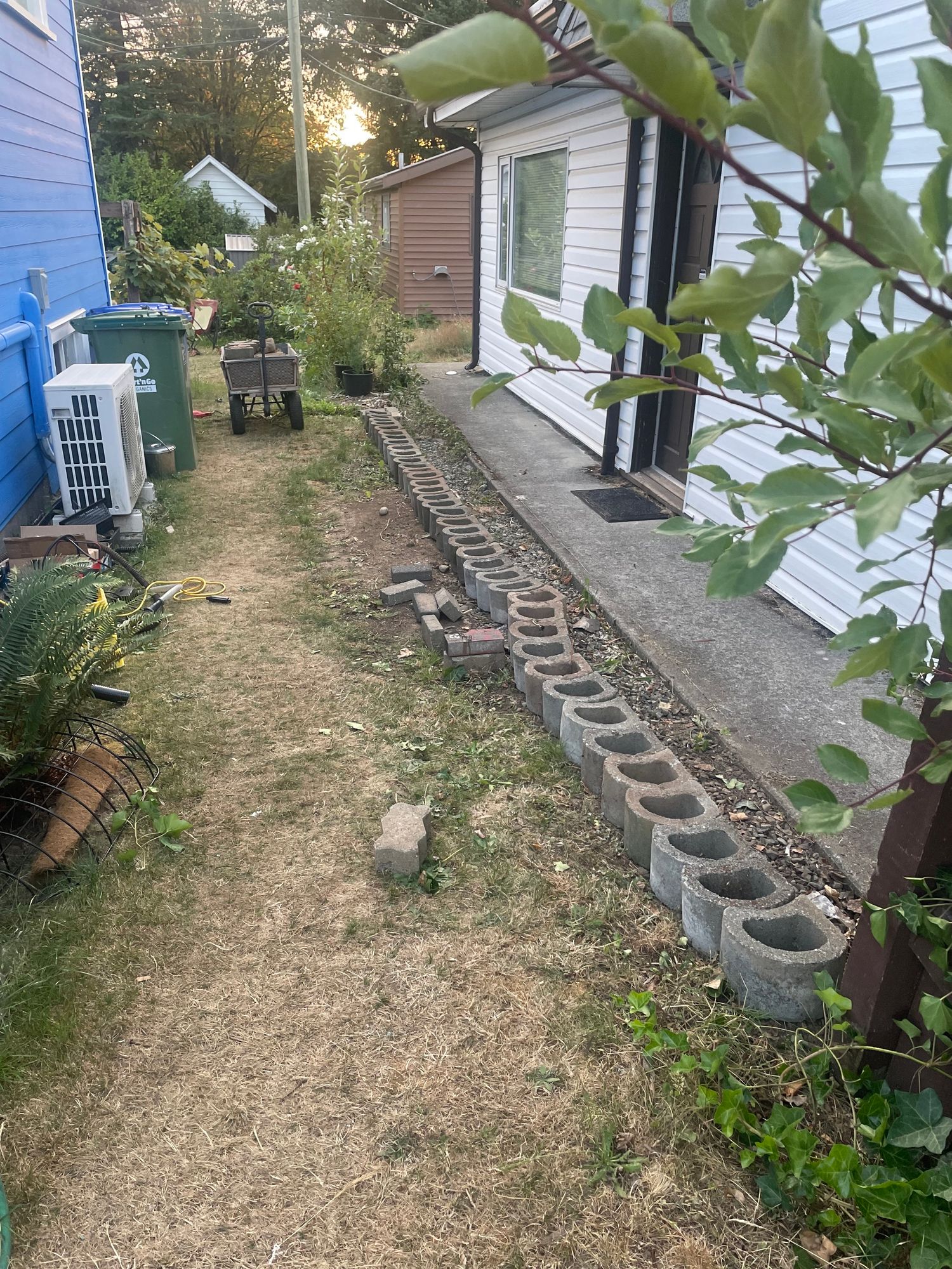 A line of D shaped cement blocks line the space between the two houses where there used to be a brown fence. This is temporary, mostly just storage for now