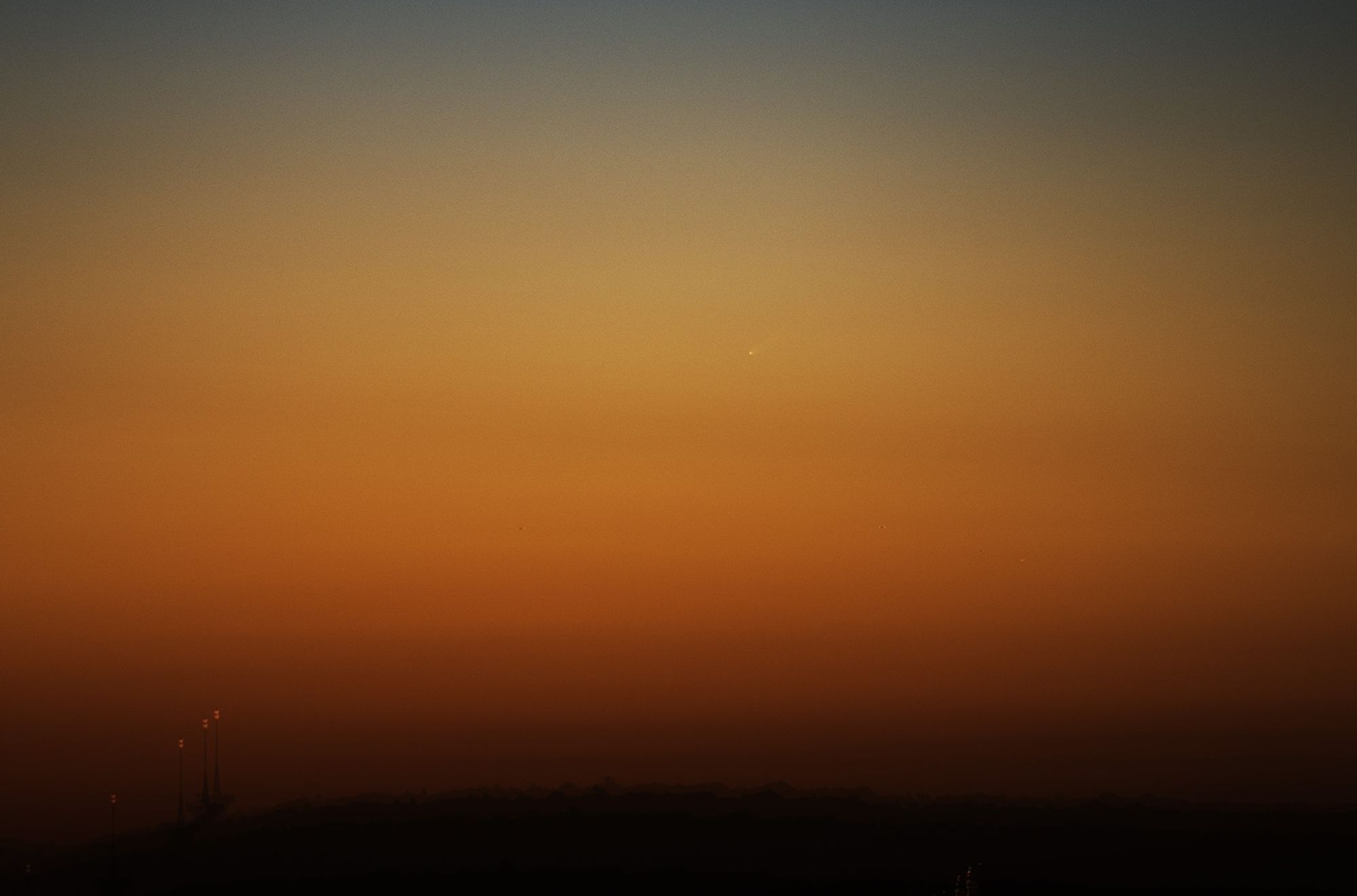 In der Morgendämmerung knapp über dem Horizont ist der Komet als fahles Licht zu sehen.